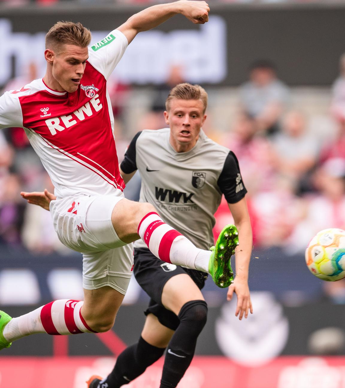 16.10.2022, Nordrhein-Westfalen, Köln: Fußball: Bundesliga, 1. FC Köln - FC Augsburg, 10. Spieltag, RheinEnergieStadion. Kölns Steffen Tigges (l) trifft zum 1:1 Ausgleich. Rechts Augsburgs Frederik Winther. 