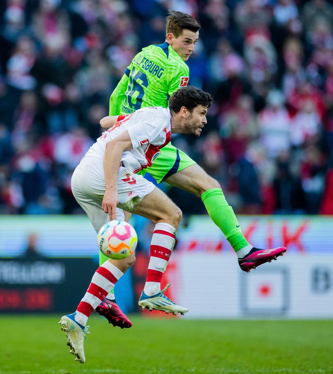 25.02.2023, Nordrhein-Westfalen, Köln: Fußball: Bundesliga, 1. FC Köln - VfL Wolfsburg, 22. Spieltag, RheinEnergieStadion. Kölns Jonas Hector (l) und Wolfsburgs Jakub Kaminski versuchen an den Ball zu kommen. 