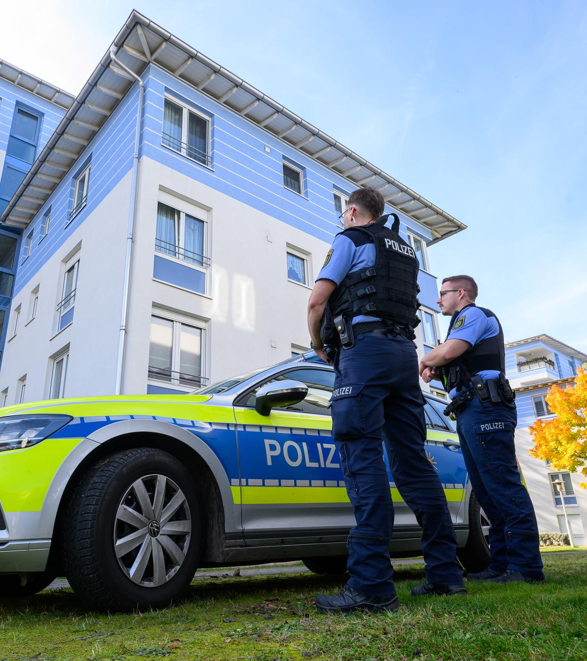 Polizisten stehen vor einem Mehrfamilienhaus in Leipzig.