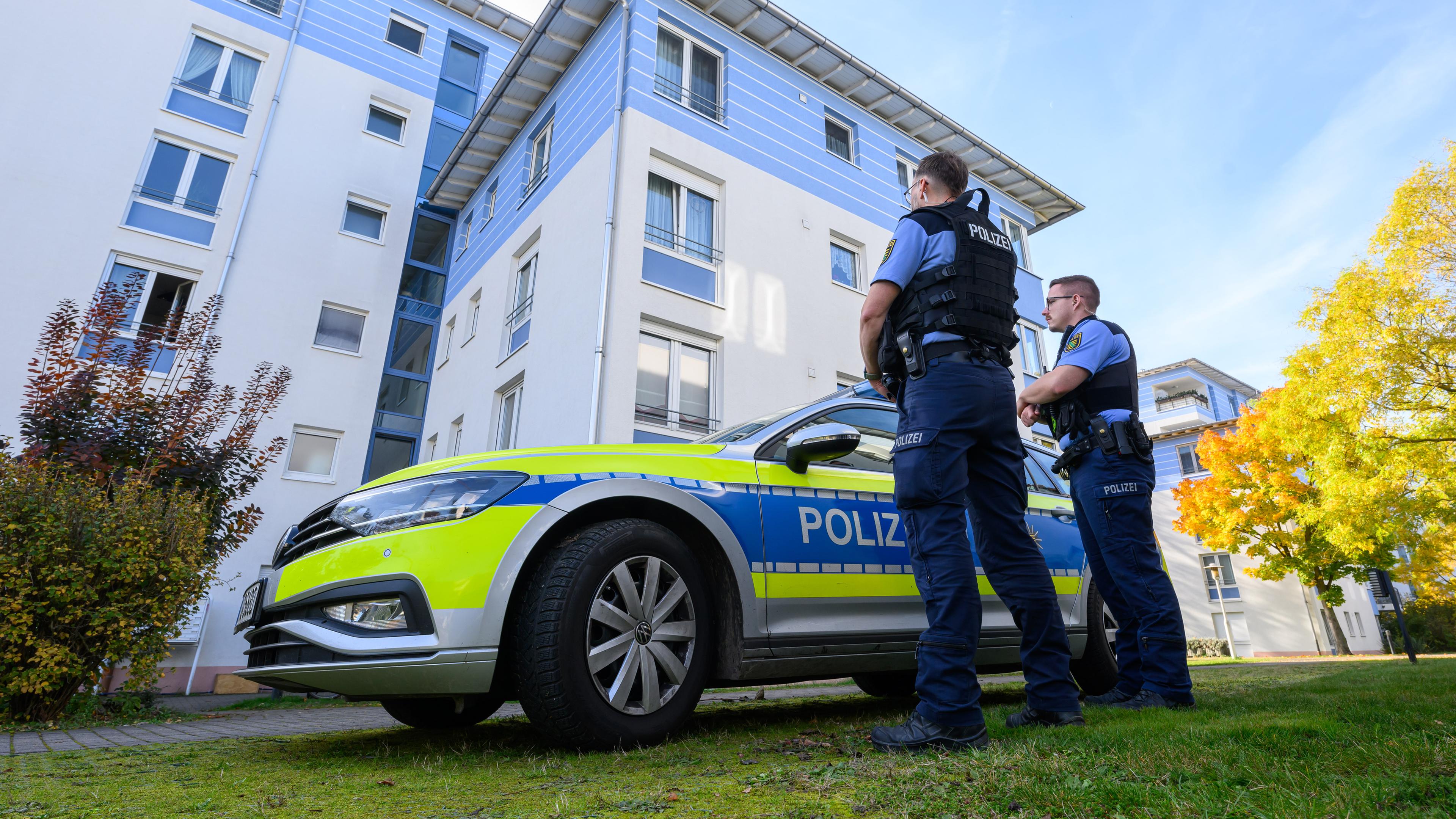 Polizisten stehen vor einem Mehrfamilienhaus in Leipzig.