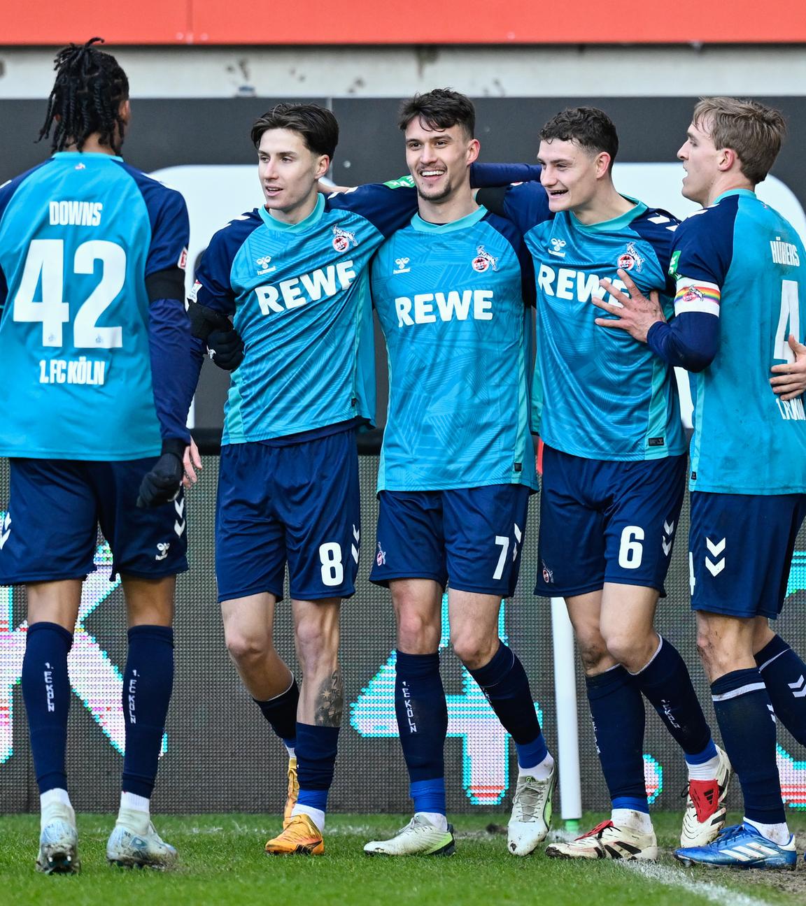 Kölns Torschütze Dejan Ljubicic jubelt mit seinen Mannschaftskollegen über das Tor zum 1:0 gegen Kaiserslautern. Die Spieler laufen Arm in Arm über den Platz und lächeln.