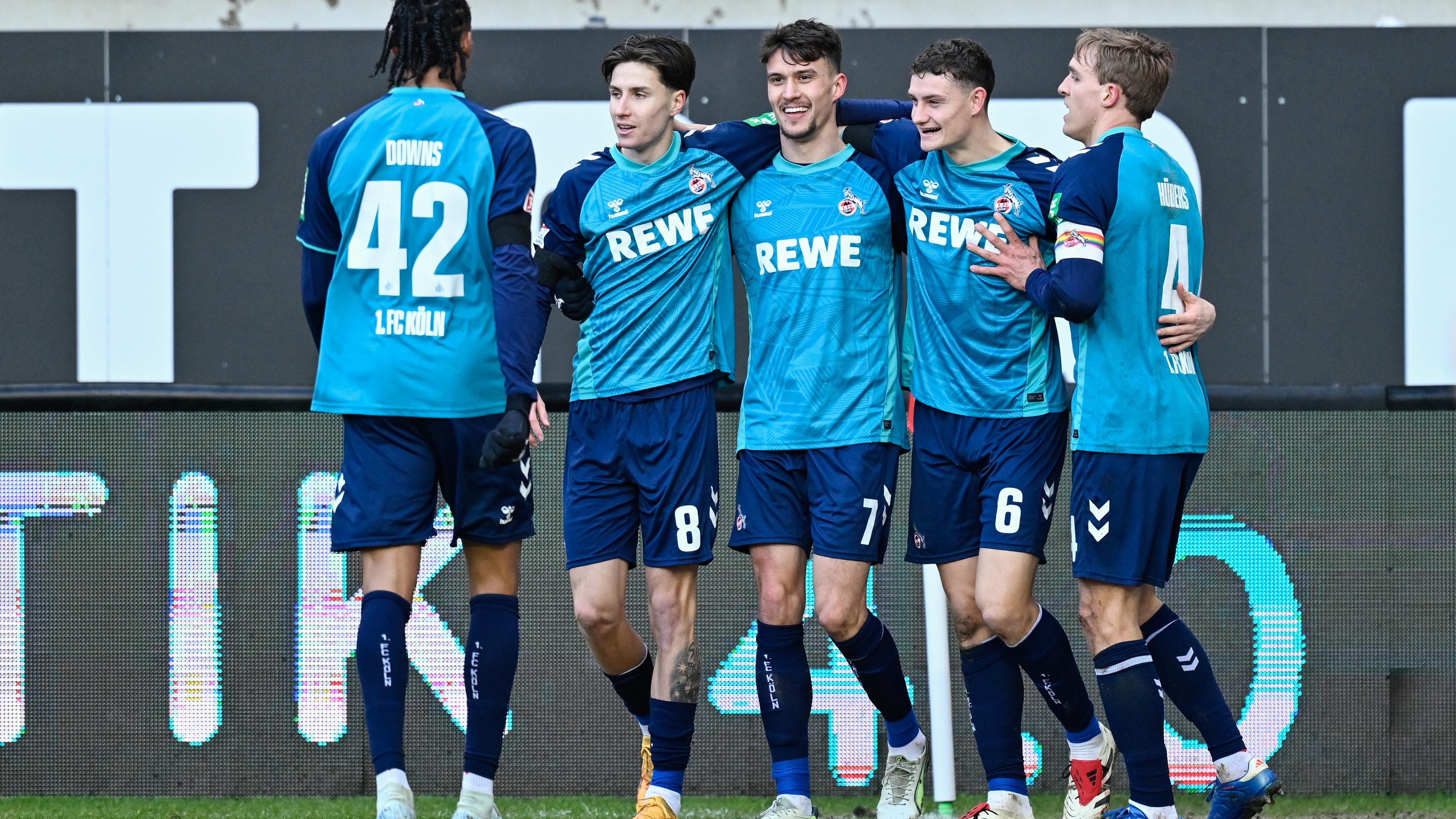 Kölns Torschütze Dejan Ljubicic jubelt mit seinen Mannschaftskollegen über das Tor zum 1:0 gegen Kaiserslautern. Die Spieler laufen Arm in Arm über den Platz und lächeln.