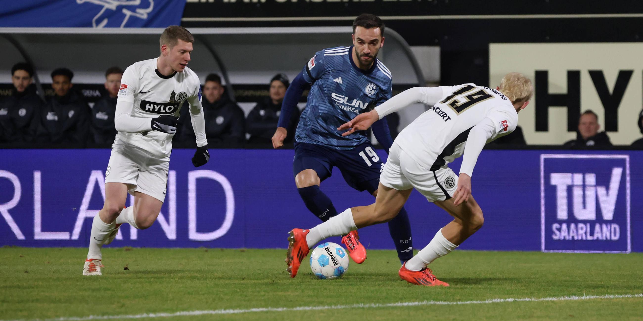 Schalkes Kenan Karamankämpft um den Ball gegen Lukas Pinckert und Elias Baum vom SV Elversberg.