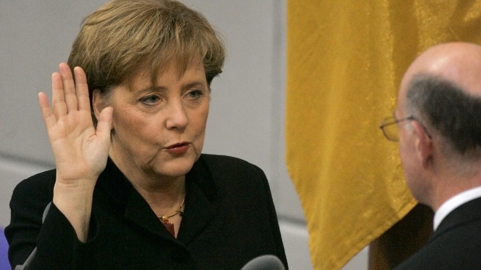 Merkel erhebt die Hand und spricht etwas dabei.