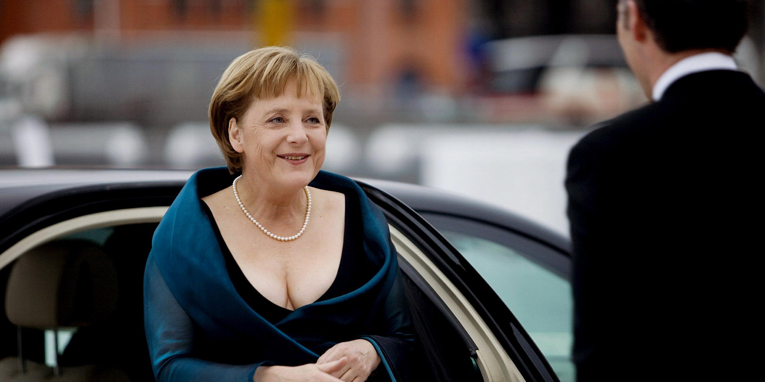 Angela Merkel ist in einem Kleid mit Perlenkette und Handtasche zu sehen. 