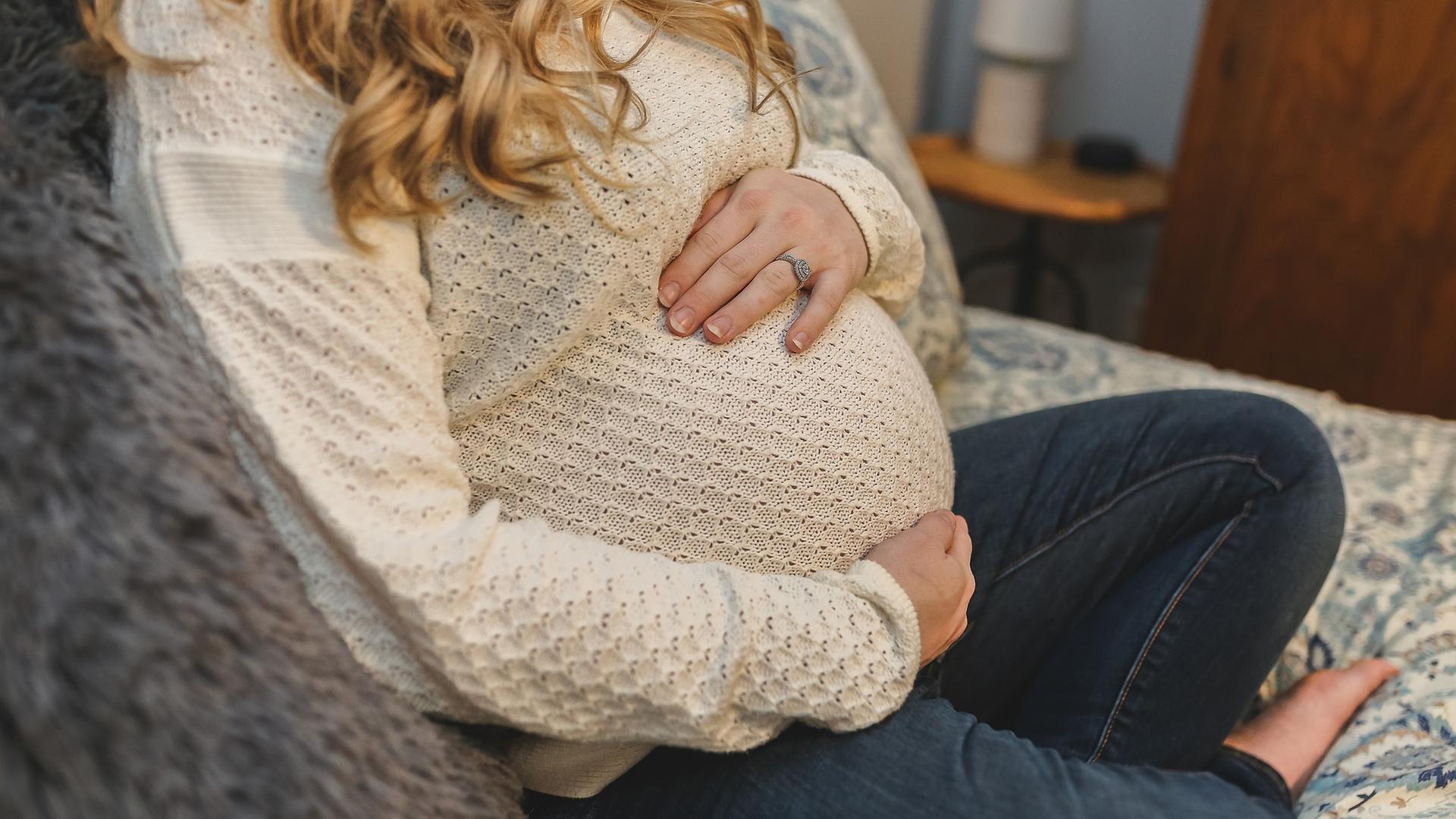 Schwangere Frau sitzt auf dem Sofa