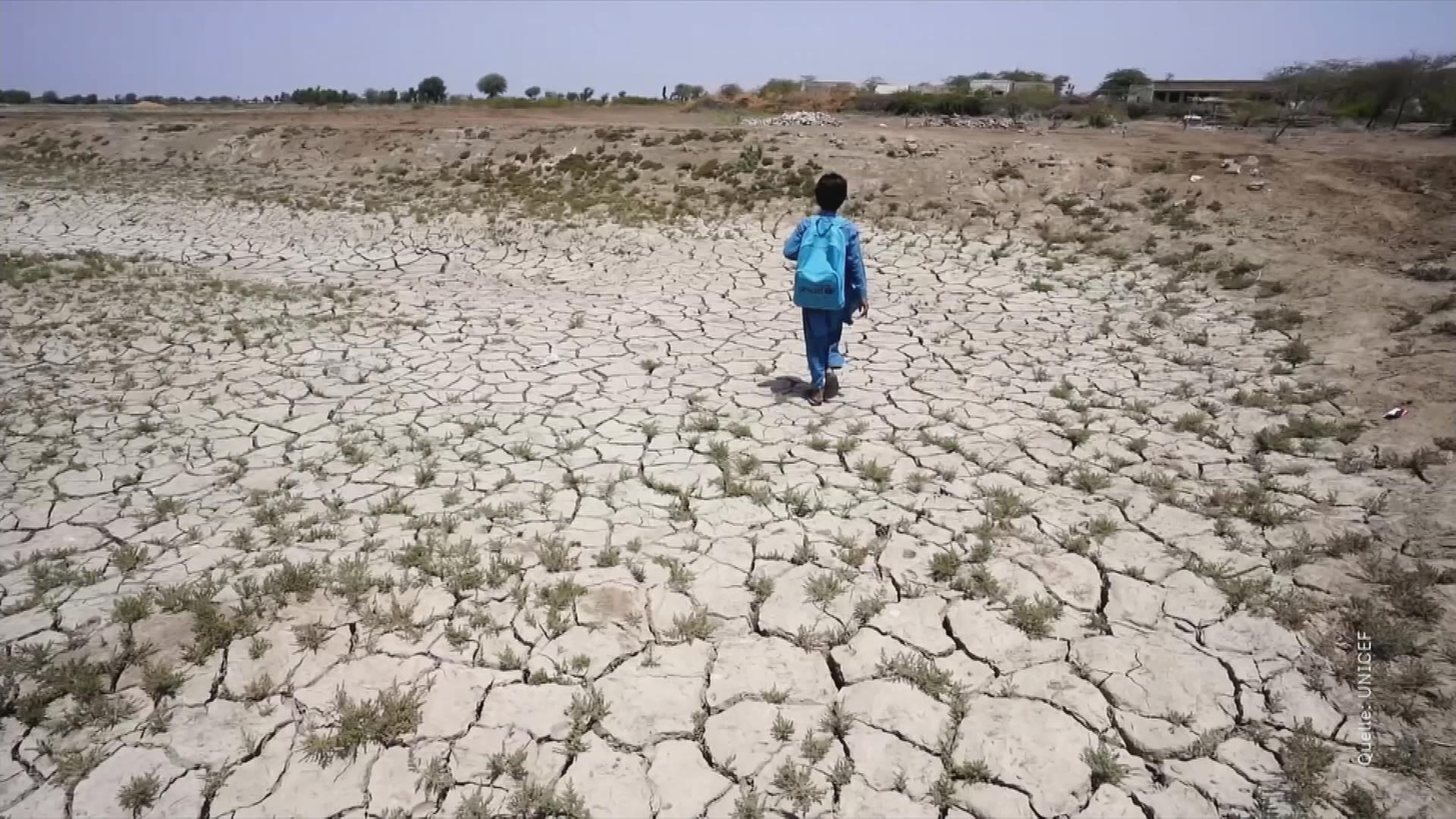 Kind läuft über Erde, die wegen Trockenheit aufgerissen ist.