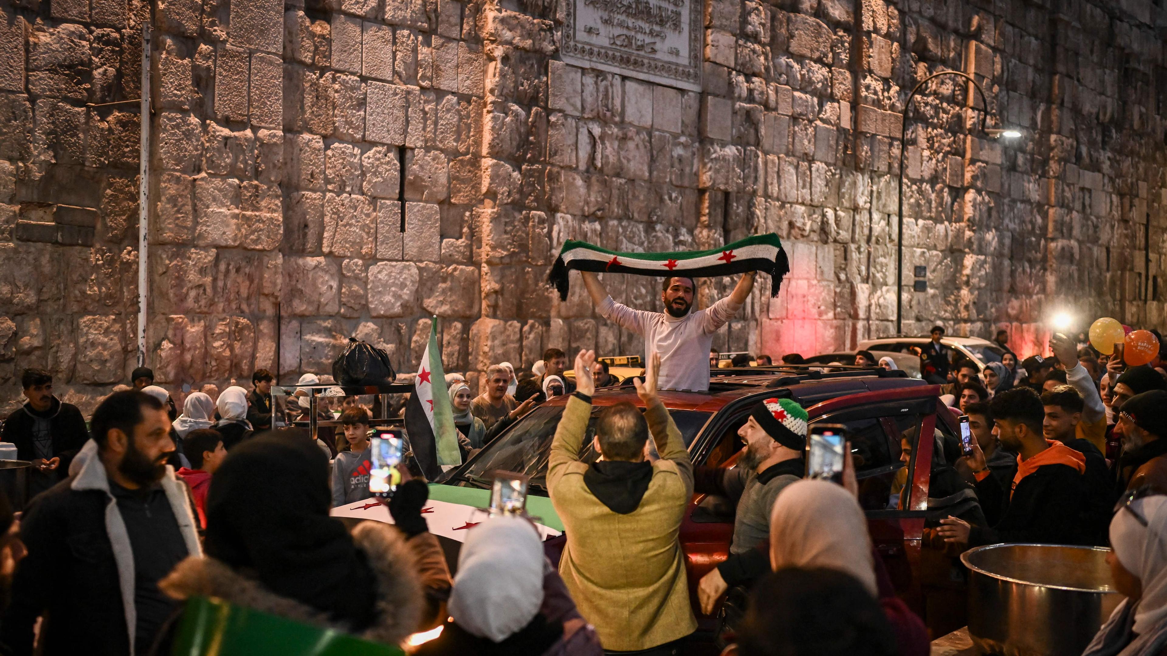 Menschen feiern vor der Ummayad-Moschee in der Altstadt von Damaskus am 11. Dezember 2024. 