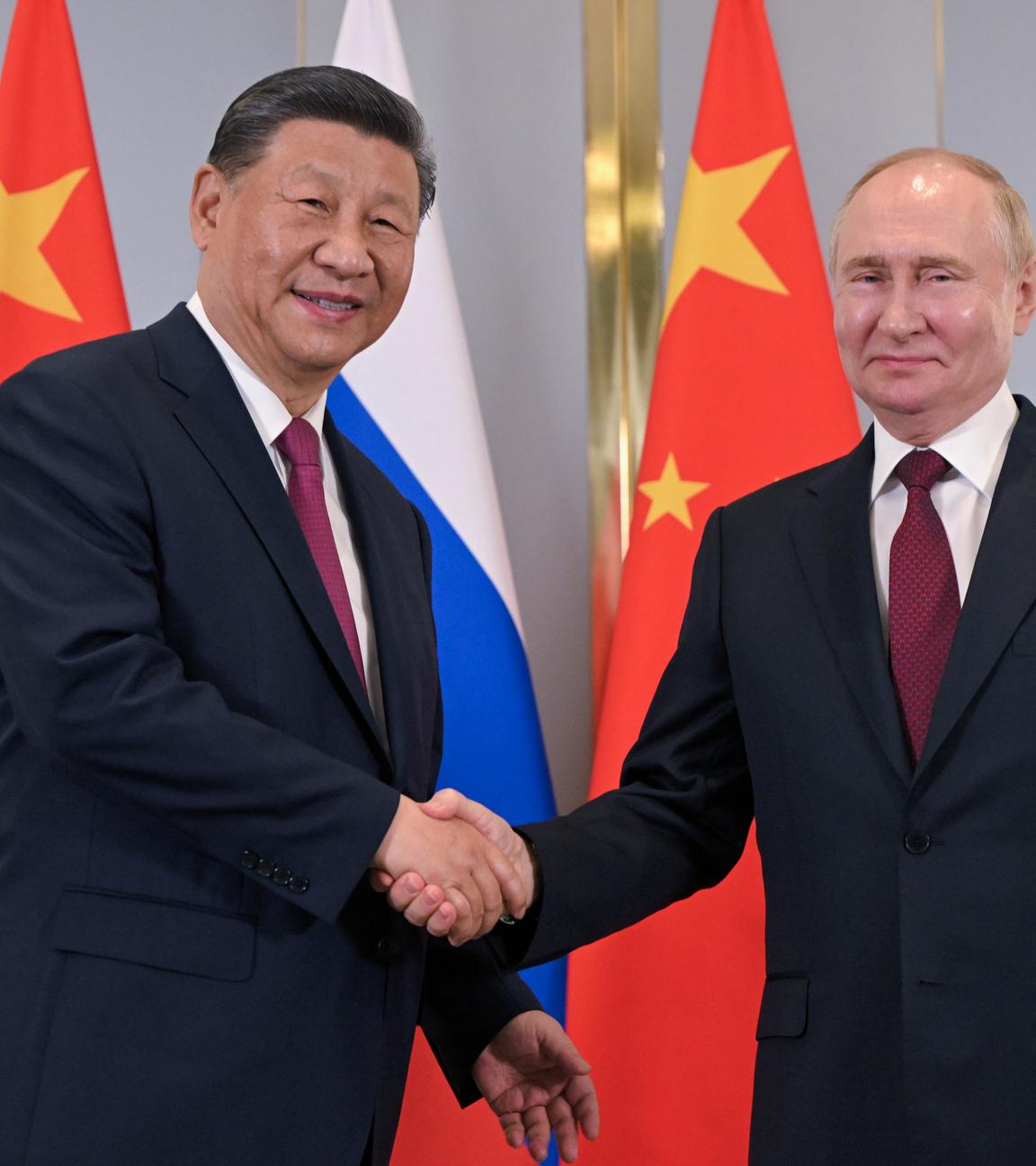 Russian President Vladimir Putin, right, and Chinese President Xi Jinping shake hands 
