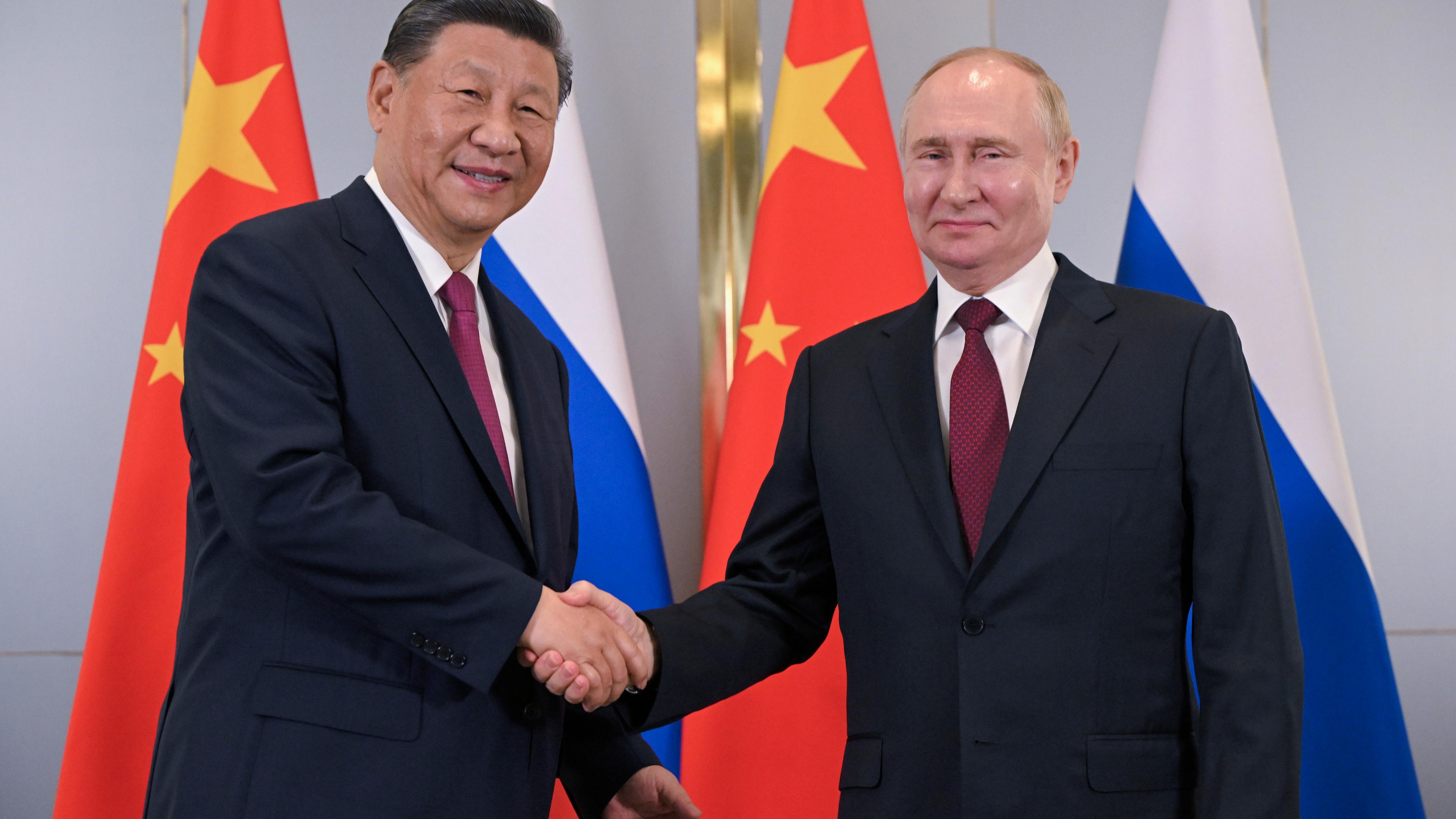 Russian President Vladimir Putin, right, and Chinese President Xi Jinping shake hands 