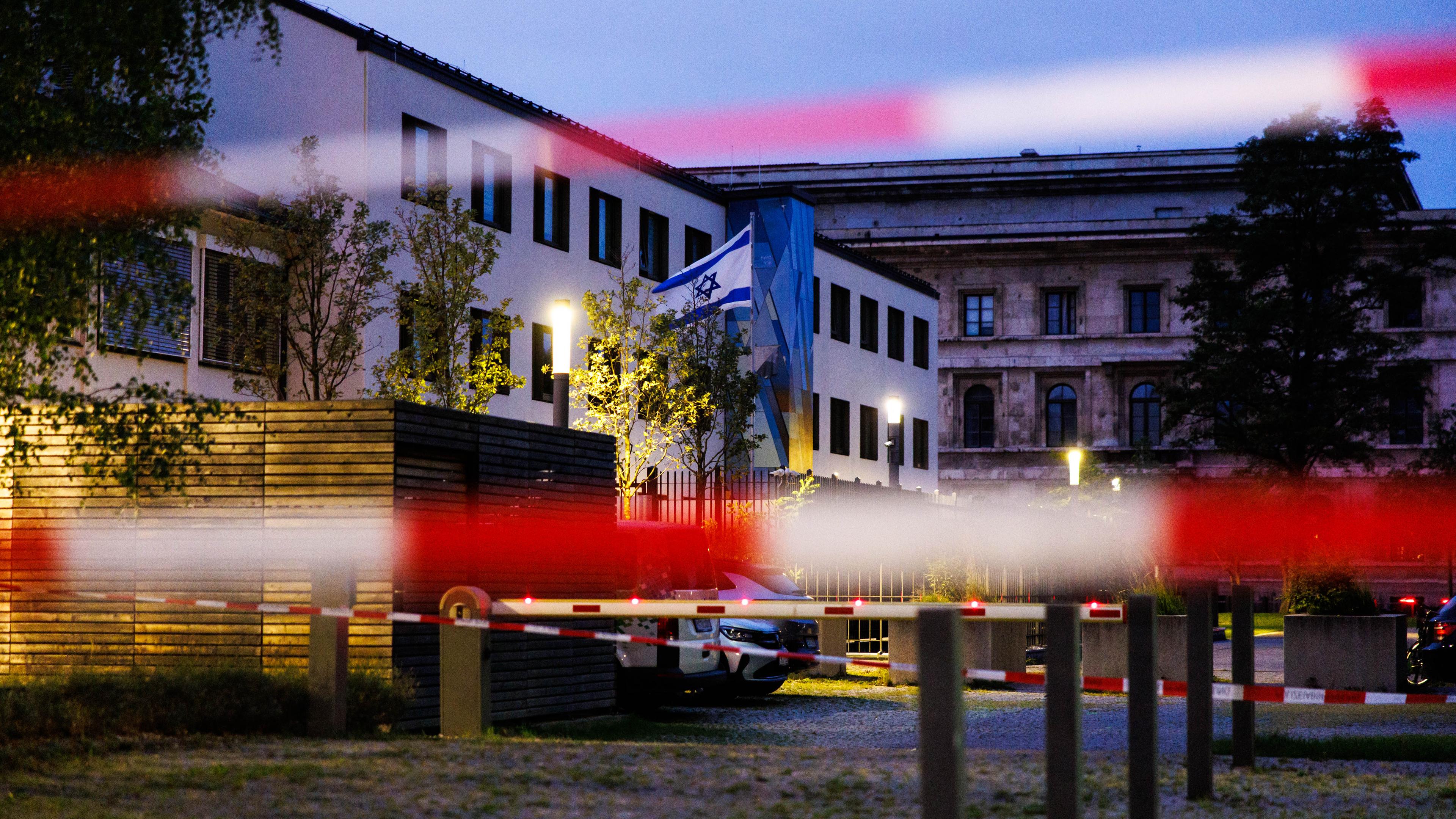 Die Fahne Israels weht am frühen Morgen vor dem Israelischen Generalkonsulat, während im Vordergrund Absperrband von der Polizei zu sehen ist. Die Polizei hat in der Münchner Innenstadt bei einem größeren Einsatz in der Nähe des Israelischen Generalkonsulats am Vortag eine verdächtige Person niedergeschossen.