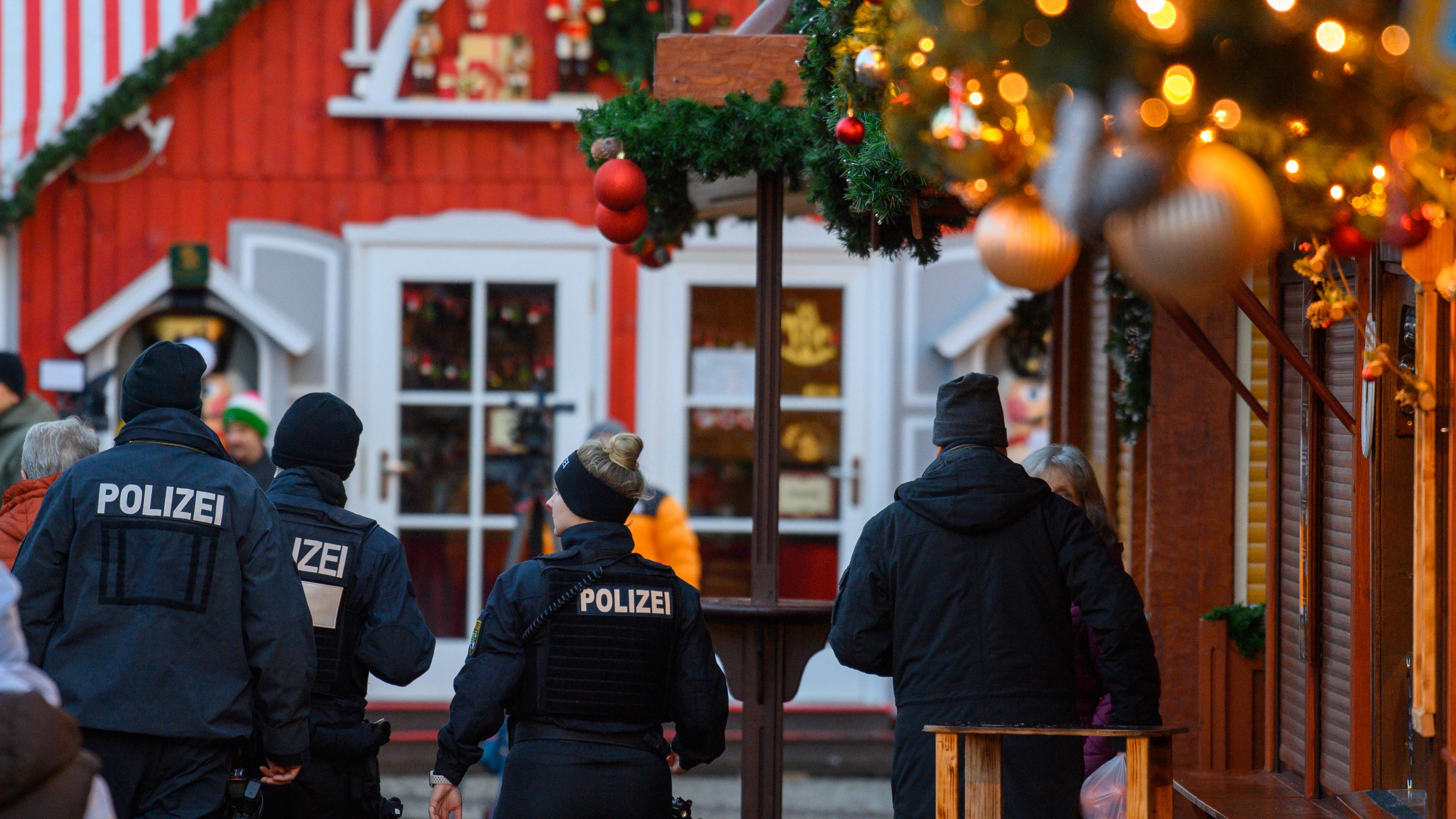  Polizisten und Passanten gehen über den geschlossenen Magdeburger Weihnachtsmarkt am 22.12.2024