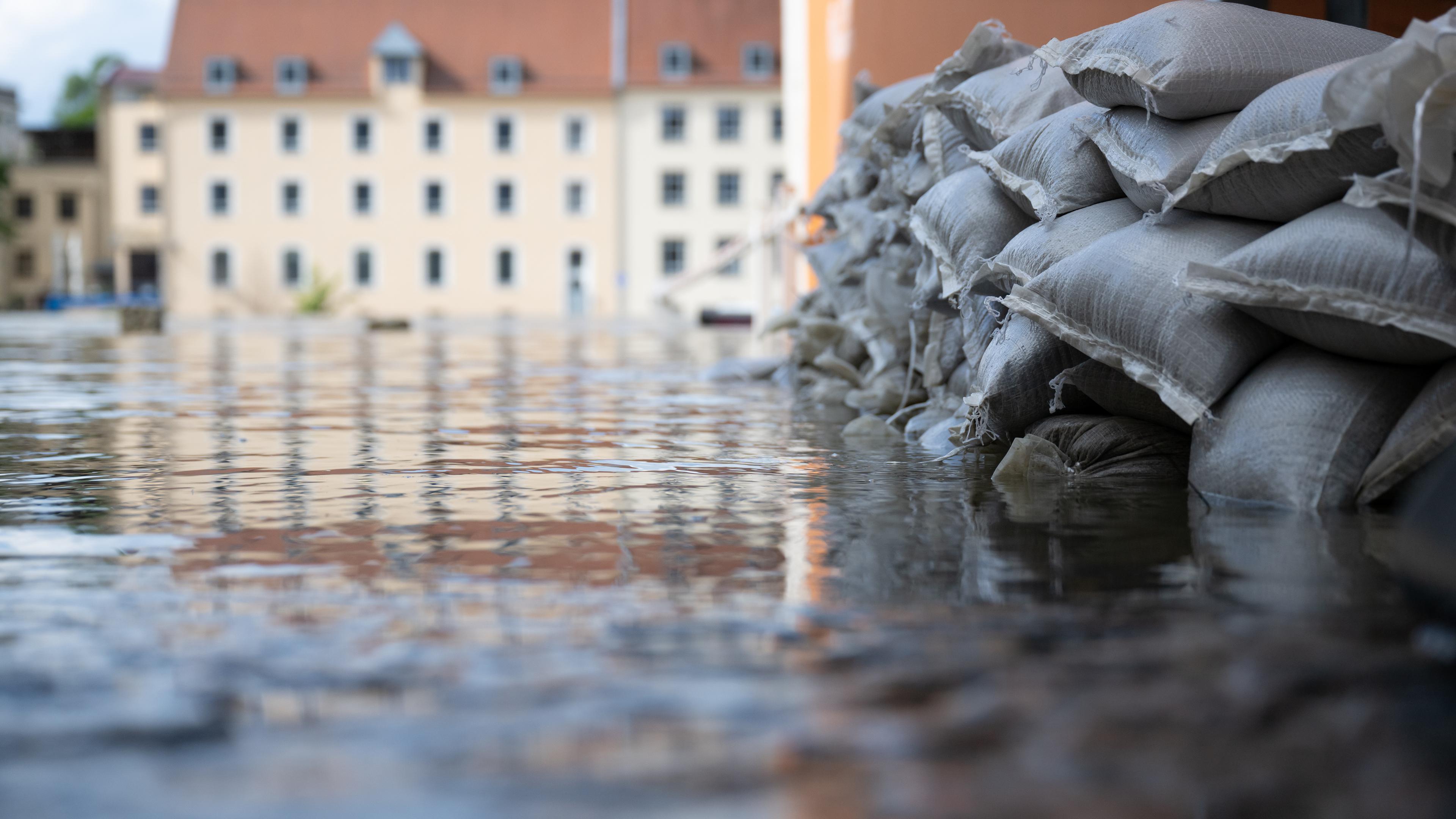 04.06.2024, Bayern, Regensburg: Sandsäcke schützen in der Altstadt am Donauufer die Einfahrt von einer Garage.