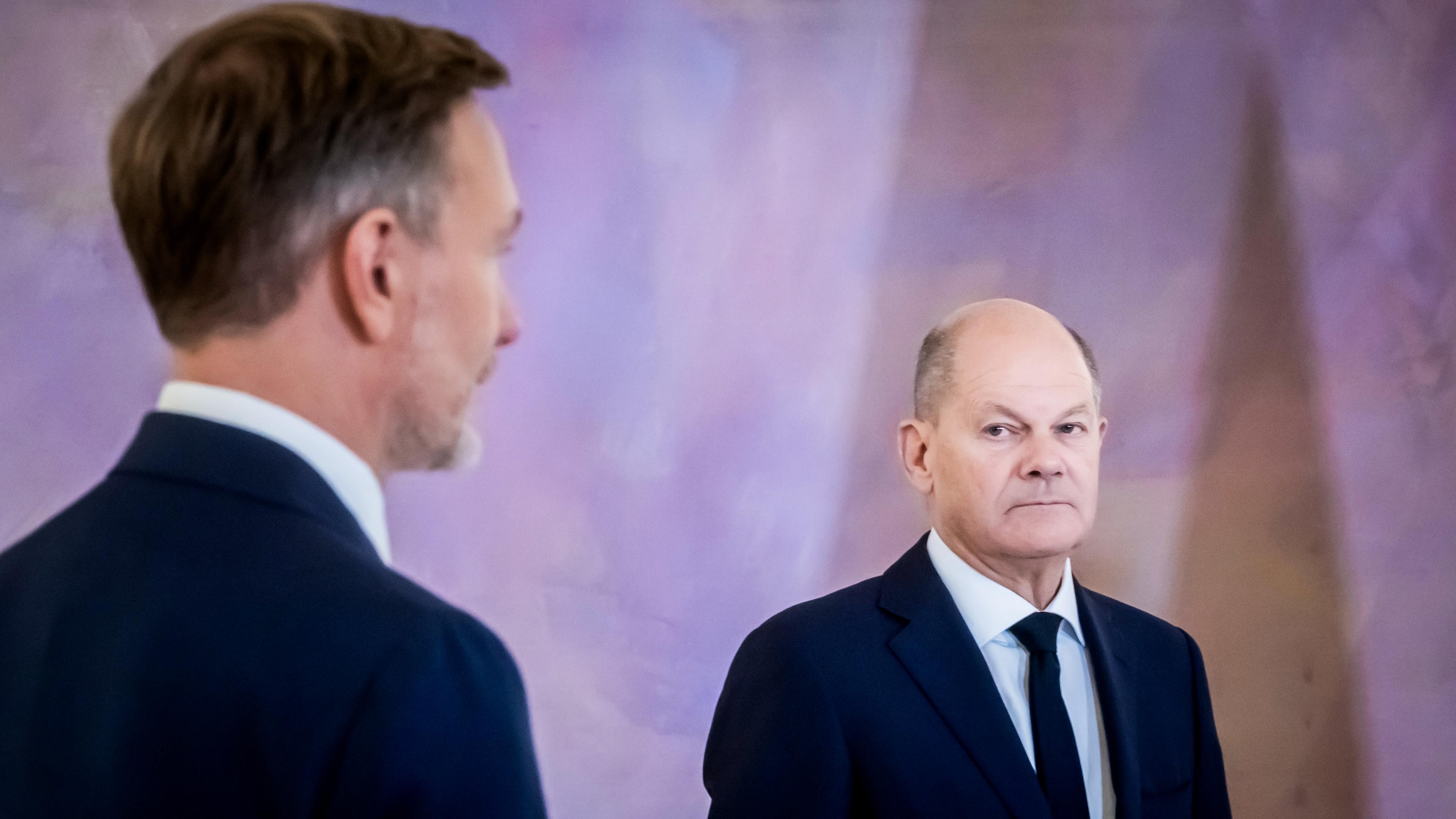 Bundeskanzler Olaf Scholz (r/SPD) schaut auf Christian Lindner (FDP), ehemaliger Bundesminister der Finanzen im Schloss Bellevue