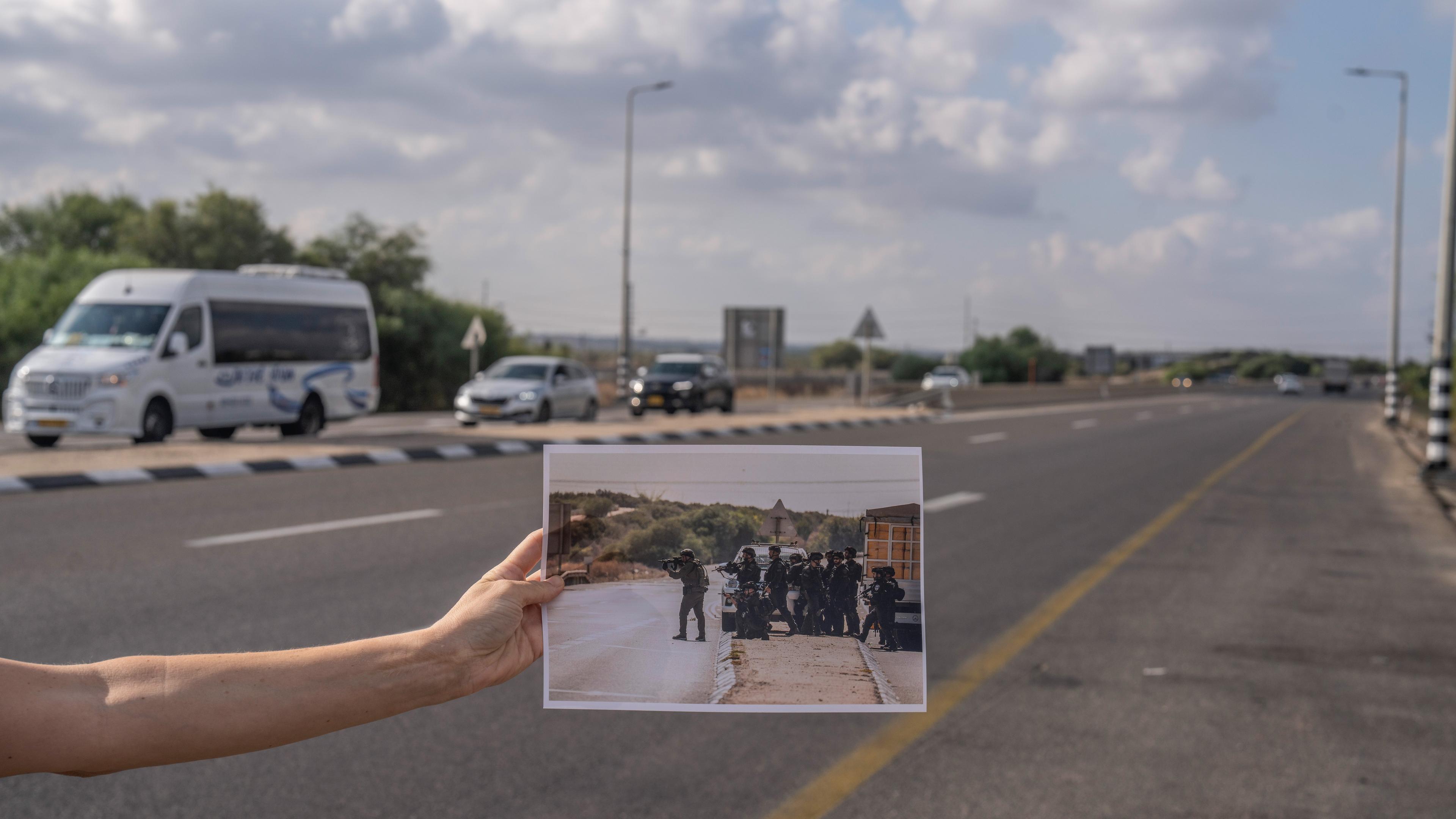 26.09.2024, Israel, Zikim: Das Bild zeigt ein Foto in der Hand einer Frau, die an derselben Stelle steht, an der das Foto vor einem Jahr aufgenommen wurde.