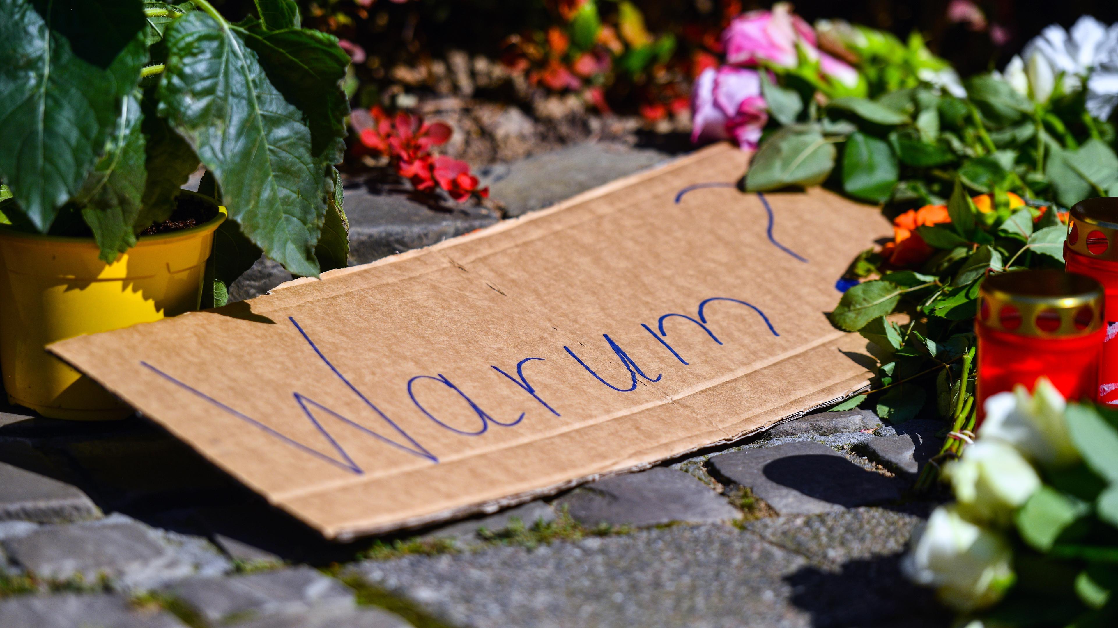 Ein Plakat mit der Aufschrift „Warum?“ inmitten von Blumen und Gedenksteinen, die nach einem Messerangriff in der Nähe des Tatorts in Solingen, Deutschland, am 24. August 2024 auf den Gehweg gelegt wurden.