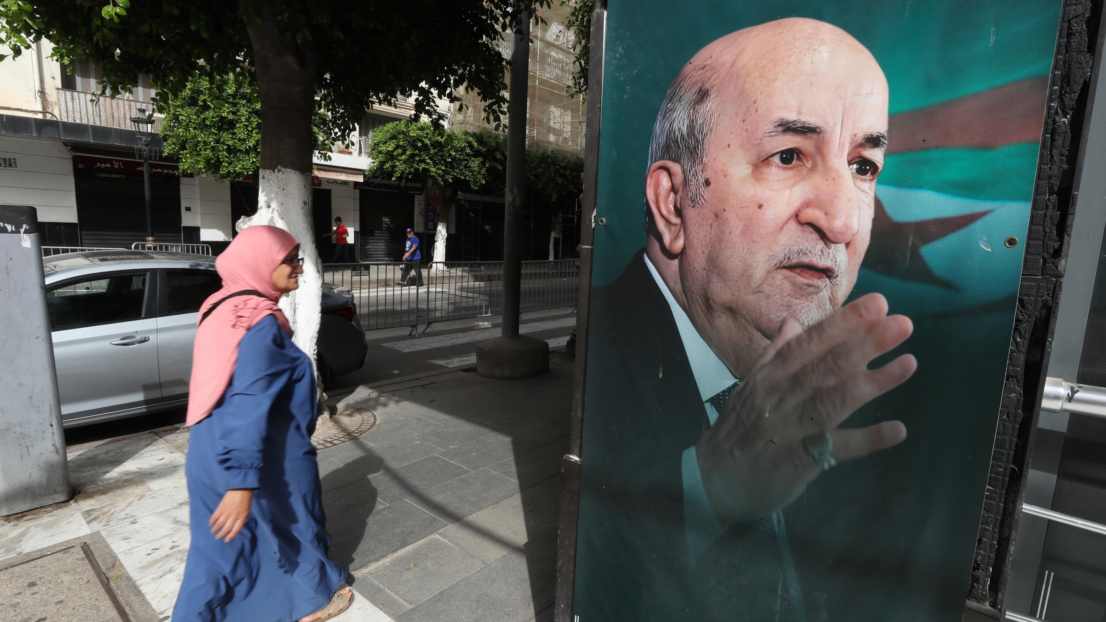 Eine Frau geht an einem Wahlbanner des amtierenden algerischen Präsidenten und des unabhängigen Präsidentschaftskandidaten Abdelmajid Tebboune vorbei, bevor die Präsidentschaftswahlen in Algier, Algerien, am 06. September 2024 stattfinden. Drei Kandidaten, darunter der algerische Präsident Abdelmajid Tebboune, treten bei den Präsidentschaftswahlen am 07. September 2024 an. 