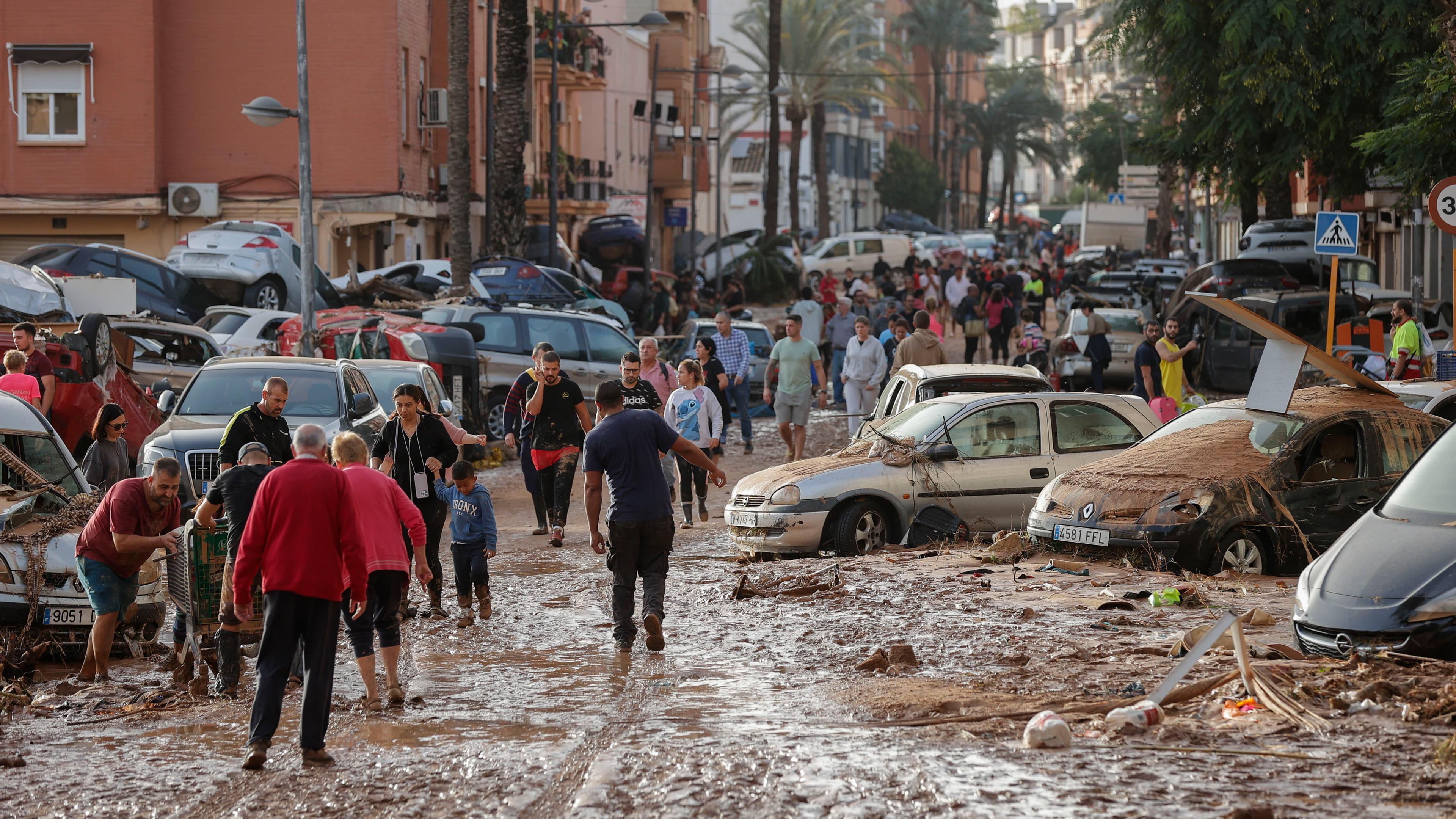 Anwohner gehen am 30. Oktober 2024 eine schlammbedeckte Straße in der vom Hochwasser betroffenen Gemeinde Paiporta in der Provinz Valencia, Spanien, entlang. Die heftigen Regenfälle im Osten des Landes haben in der Provinz Valencia und den angrenzenden Provinzen mindestens 70 Menschenleben gefordert, die von den Überschwemmungen betroffen waren.