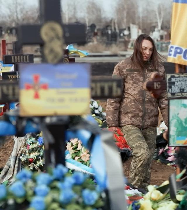 Auf dem Bild ist eine Soldatin auf dem Friedhof zu sehen.
