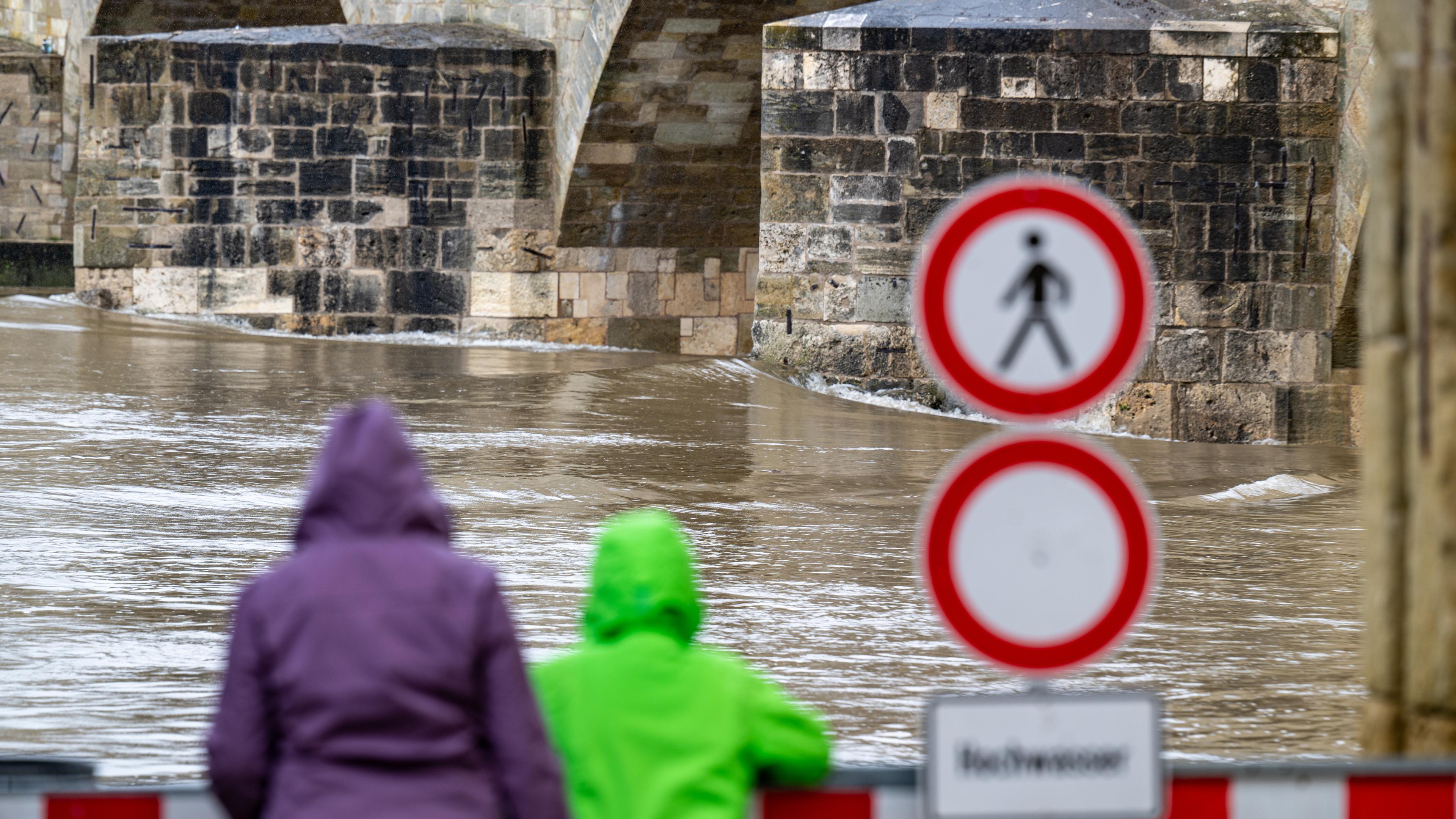 Hochwasser: Zwei Menschen schauen im Regen auf den Fluss