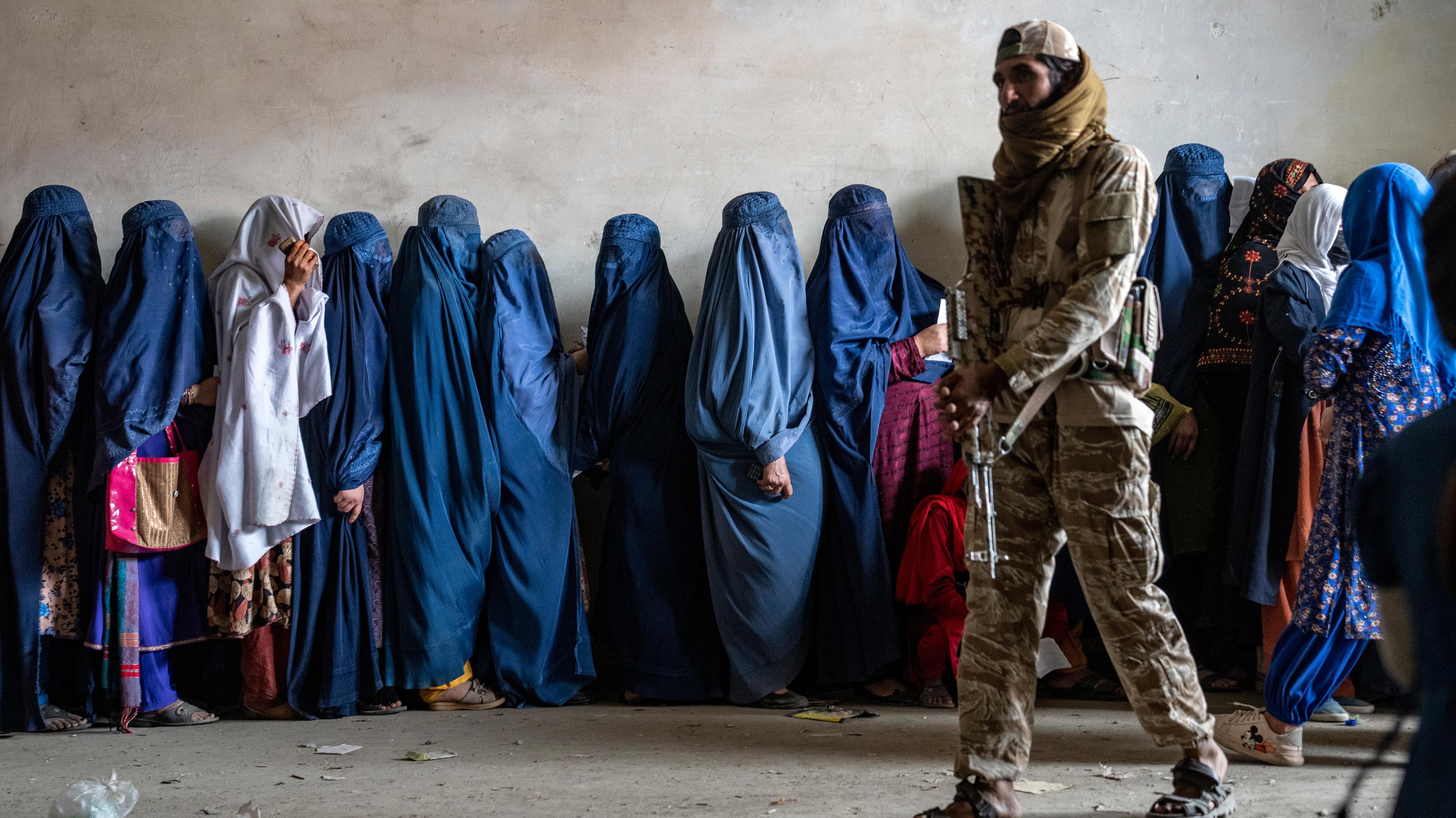 Taliban-Soldat und verschleierte Frauen