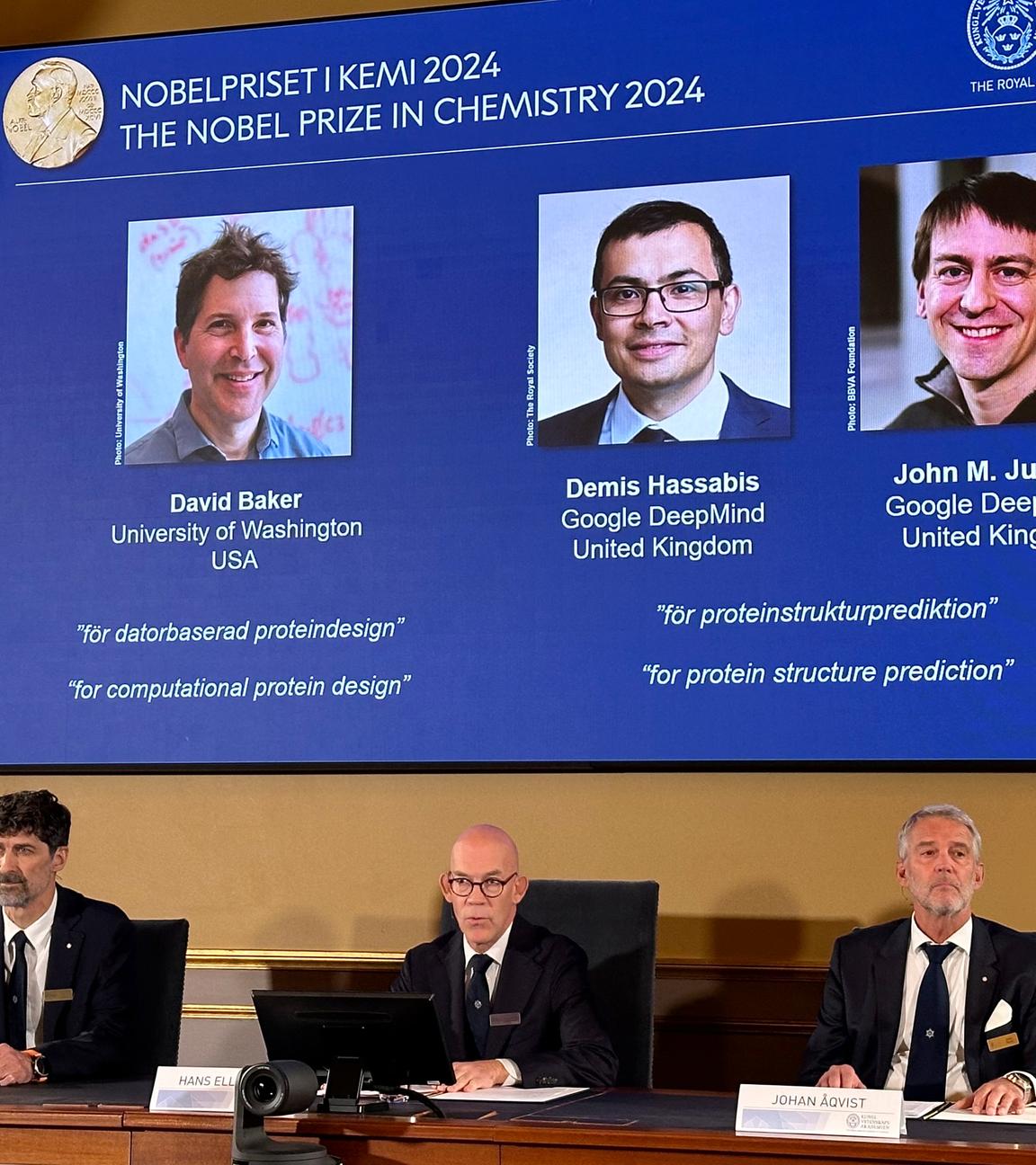 Bekanntgabe Nobelpreis 2024 für Chemie - Gremium vor Videoleinwand mit Preisträgern David Baker, Demis Hassabis und John M. Jumper