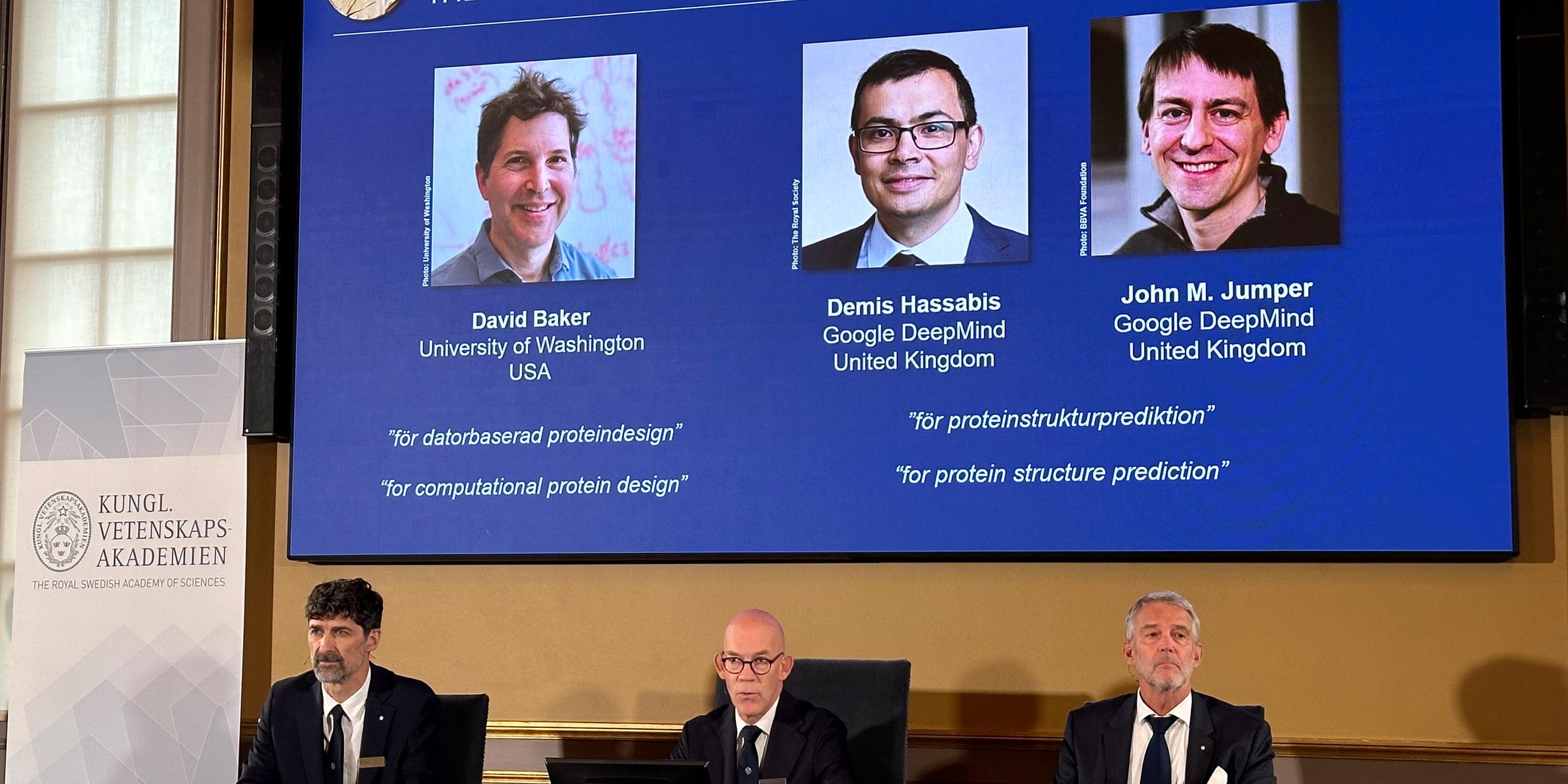 Bekanntgabe Nobelpreis 2024 für Chemie - Gremium vor Videoleinwand mit Preisträgern David Baker, Demis Hassabis und John M. Jumper