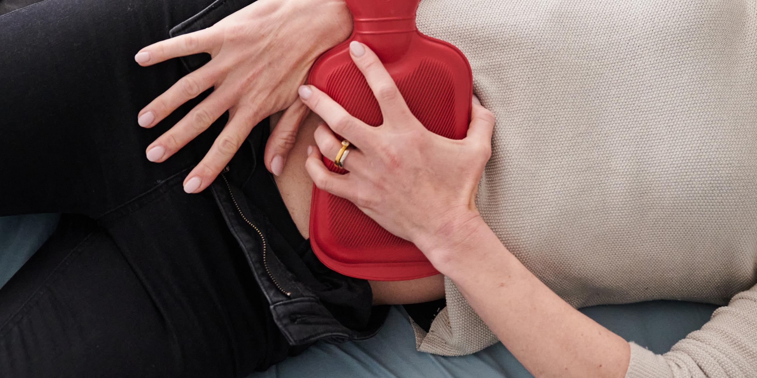 Frau hält sich eine Wämflasche auf den Bauch