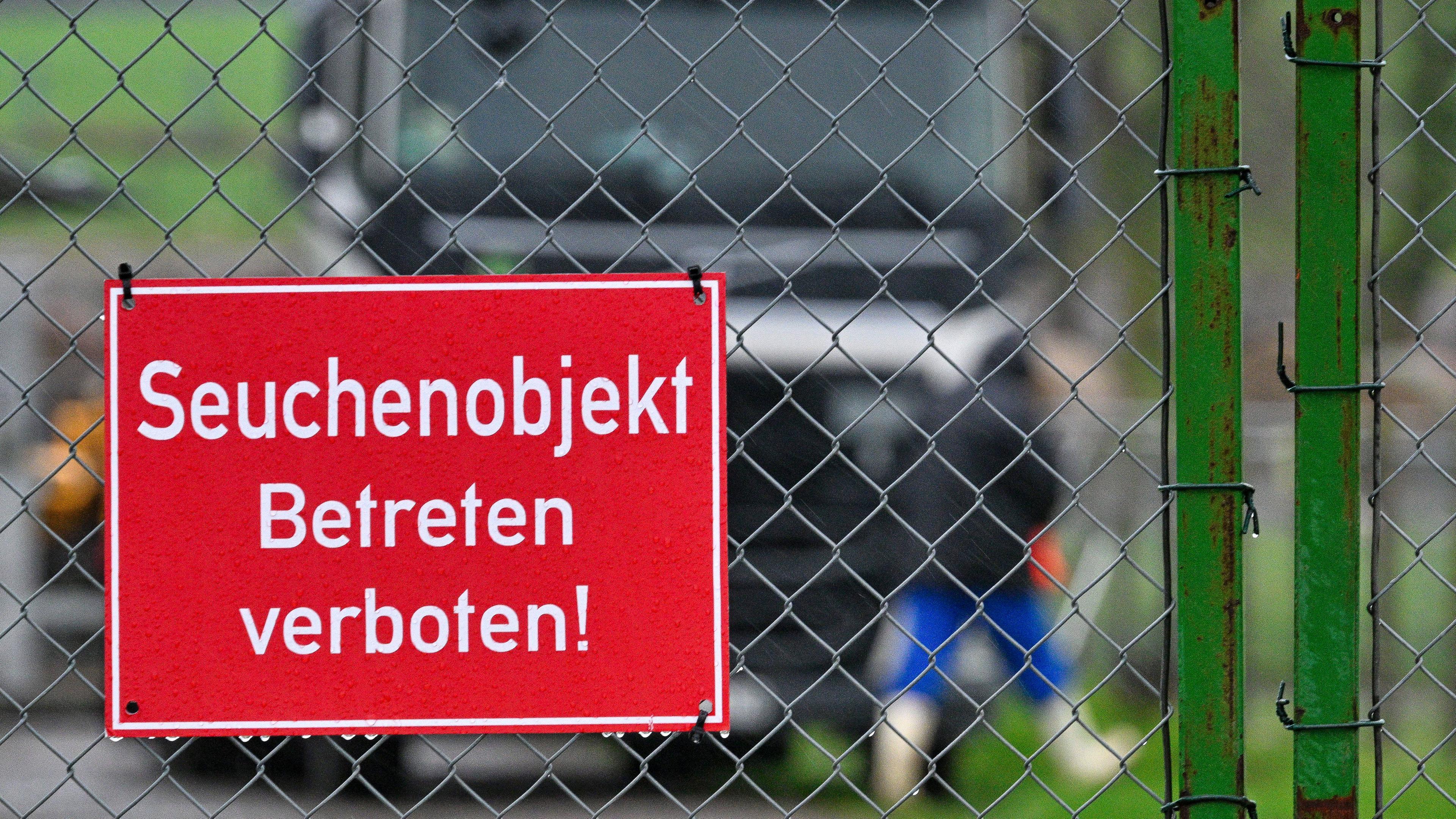 Rotes Schild mit der Aufschrift "Seuchenobjekt - Betreten verboten", montiert an einem Zaun