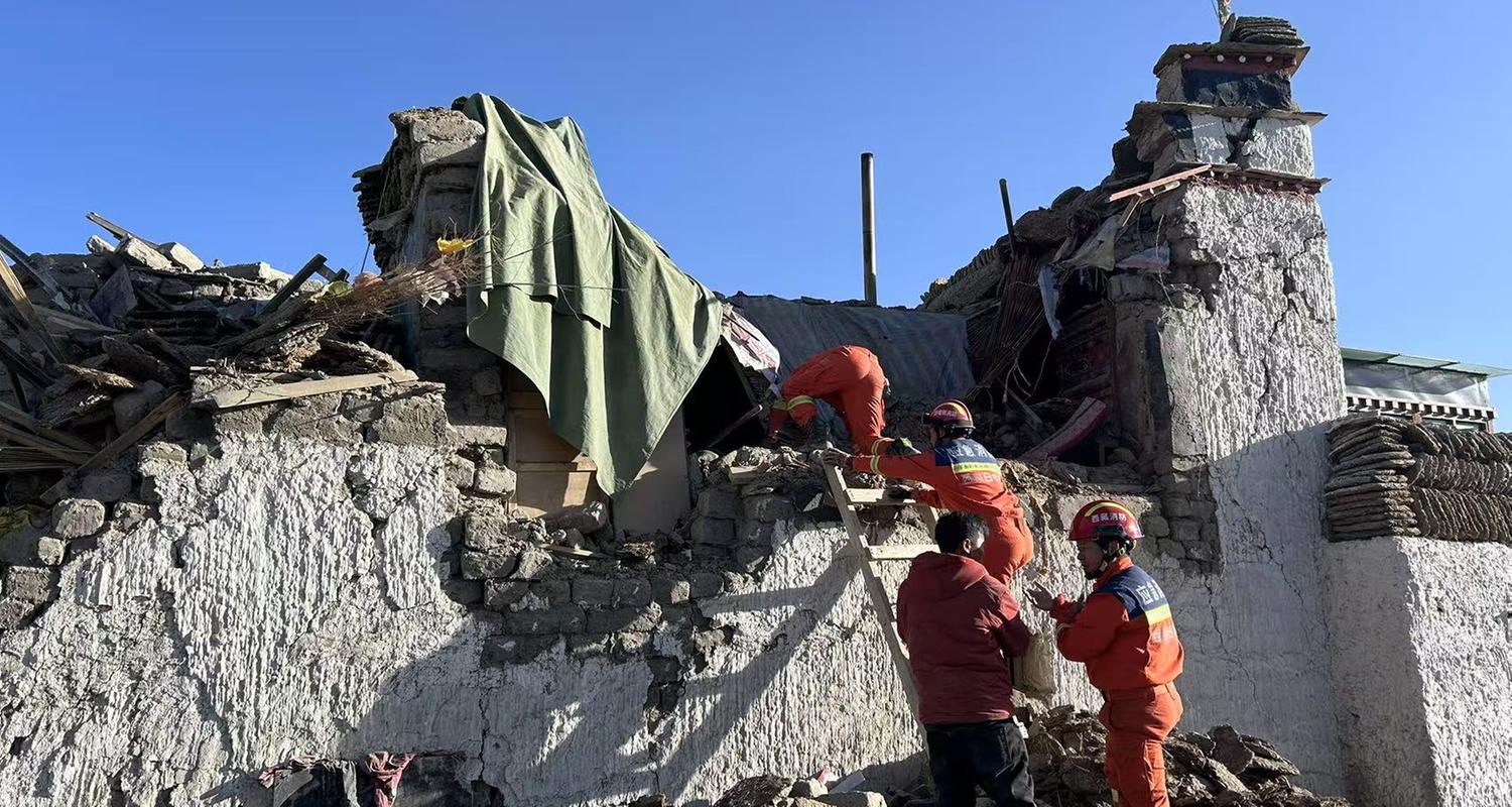 Es sind Rettungskräfte zu sehen, welche vor einen betroffenen zerstörten Haus stehen.