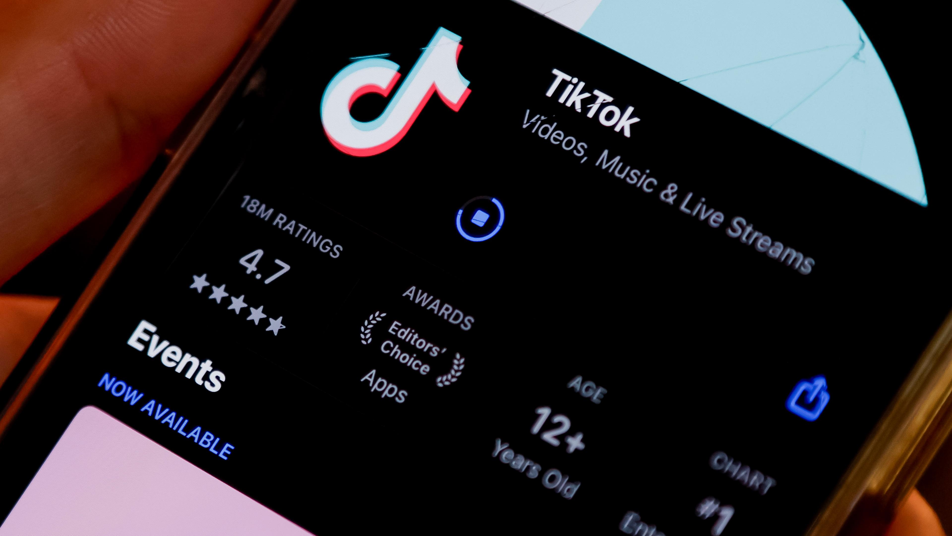 Eine Person hält ein Handy in der Hand, auf dem die TikTok App heruntergeladen wird