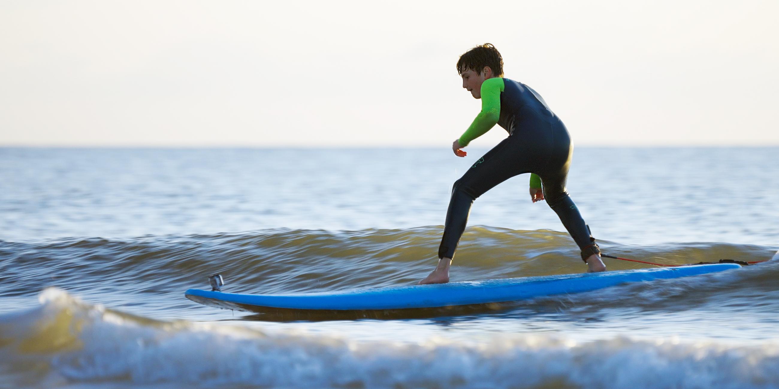 Junger Surfer auf dem Brett im Wasser.