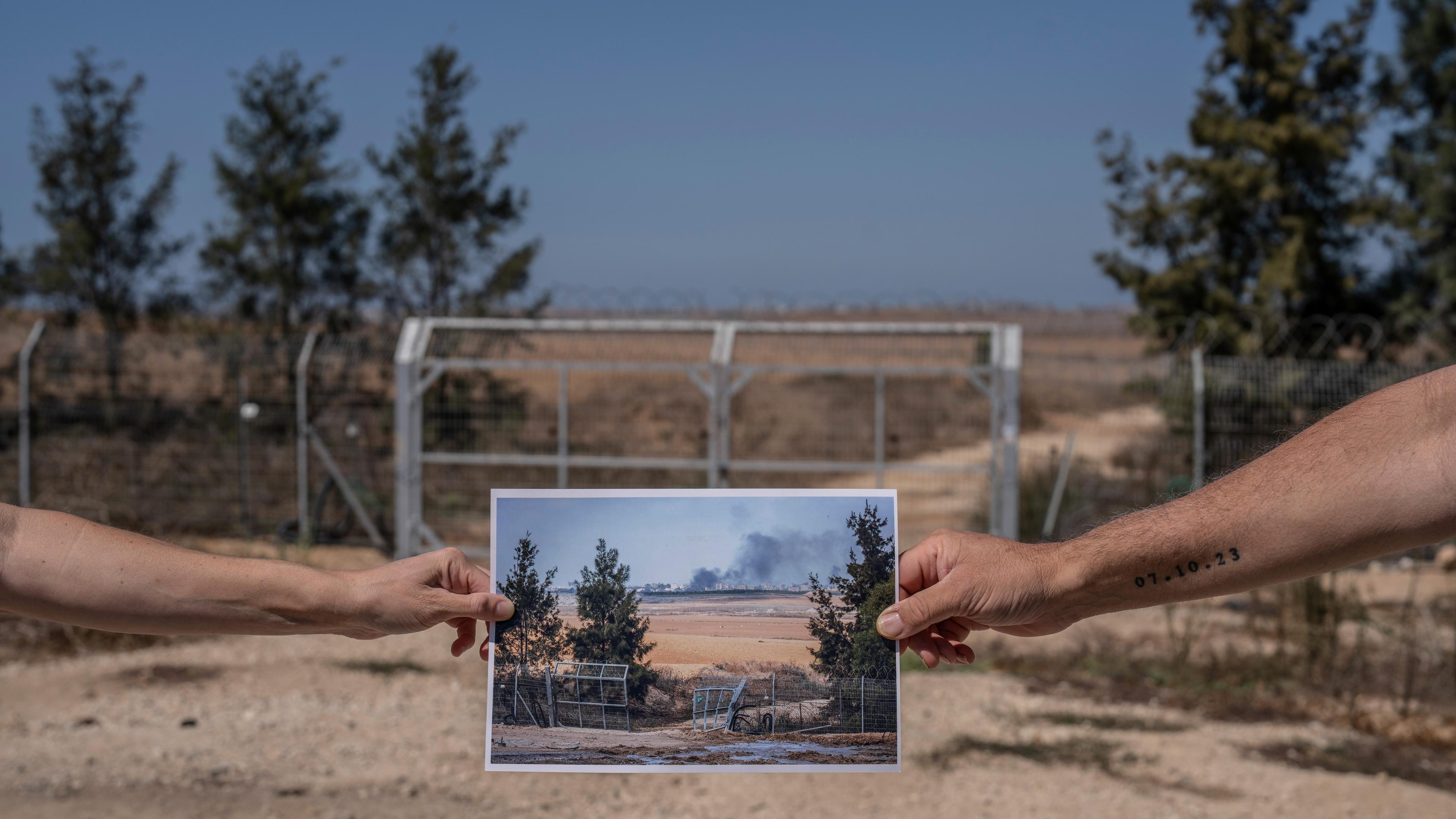 Zwei Menschen halten ein Foto, das die zerstörte Barriere zum Gazastreifen inmitten der Kämpfe zwischen Israel und der Hamas am 10. Oktober 2023 zeigt, aufgenommen an der gleichen Stelle am 26. September 2024.