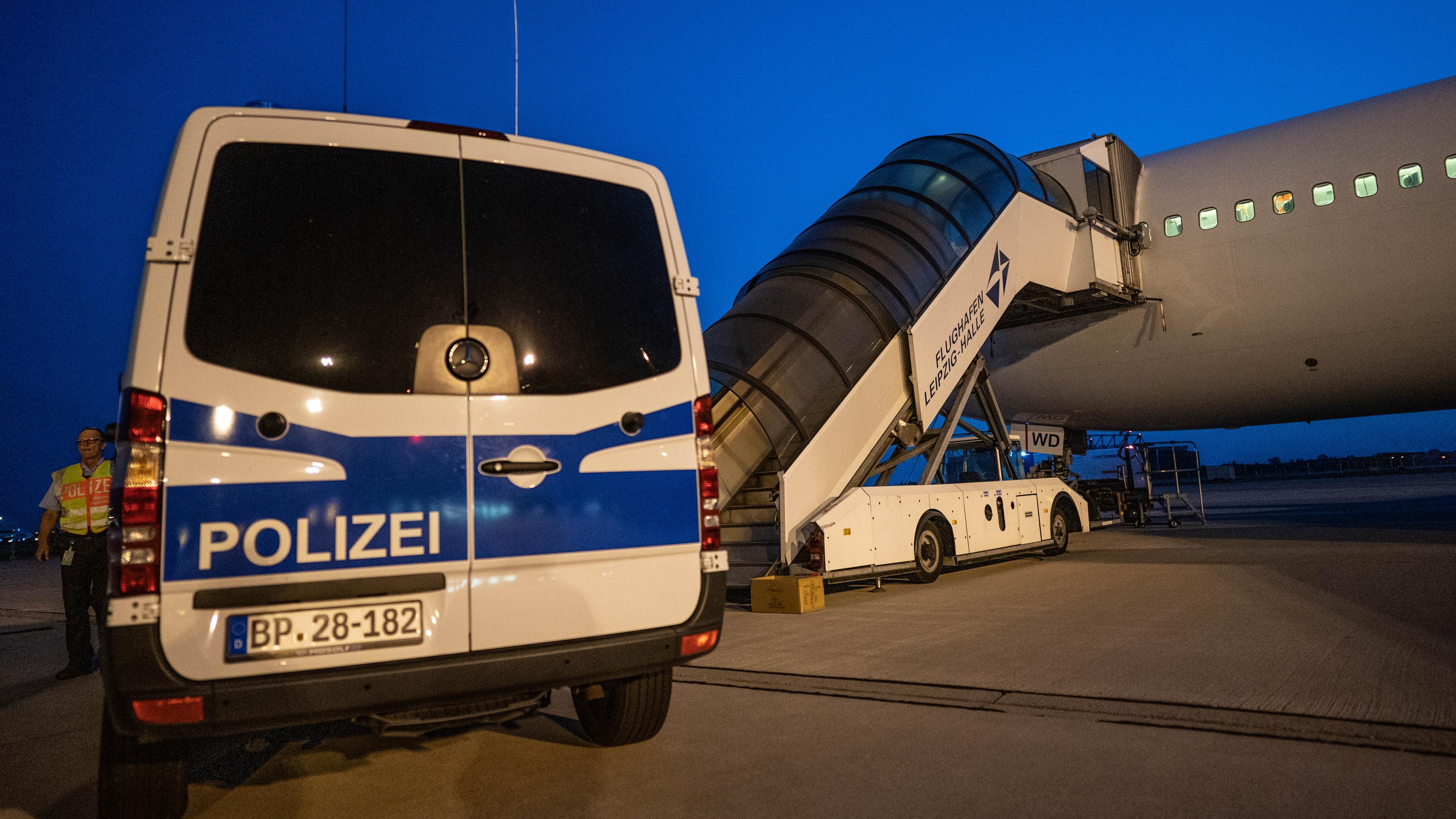 Ein Polizeifahrzeug steht vor einem Flugzeug in Leipzeig bei der Abschiebung von abgelehnten Asylbewerbern nach Afghanistan.