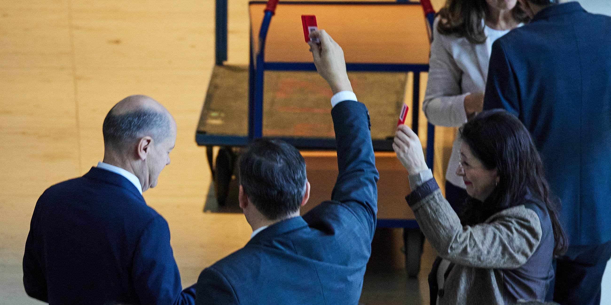 Bundeskanzler Olaf Scholz (l, SPD) gibt bei der 195. Sitzung des Deutschen Bundestages namentlich seine Stimme zum ·Sicherheitspaket· ab.