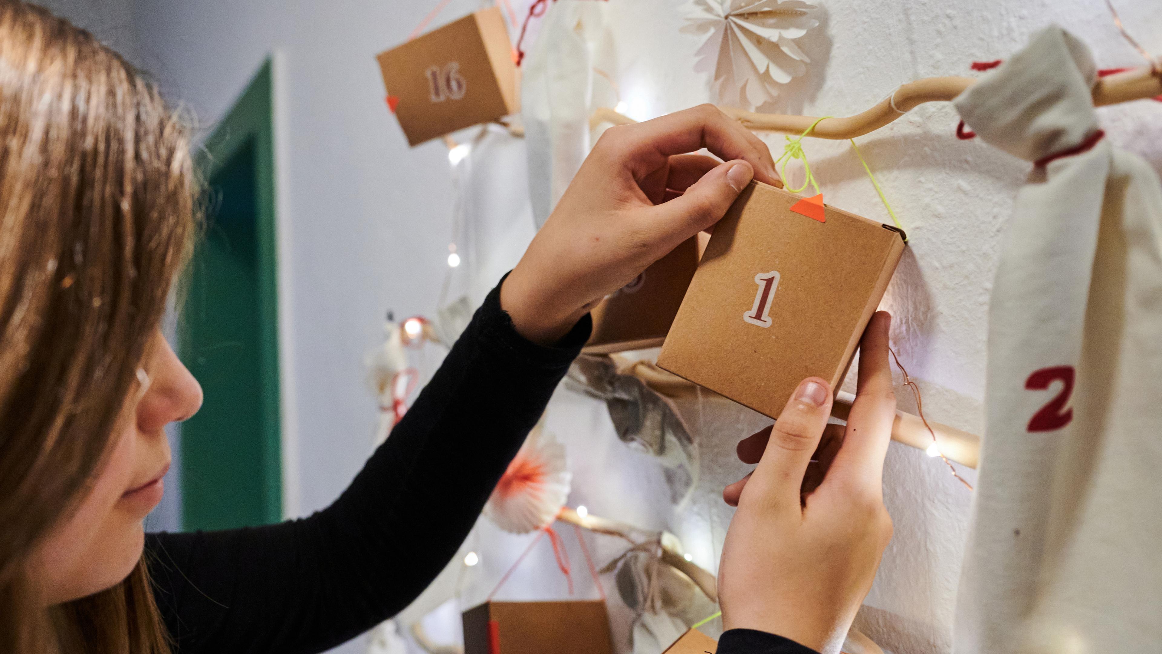 Eine Frau hält ein Päckchen eines selbst gebastelten Adventskalenders in den Händen.