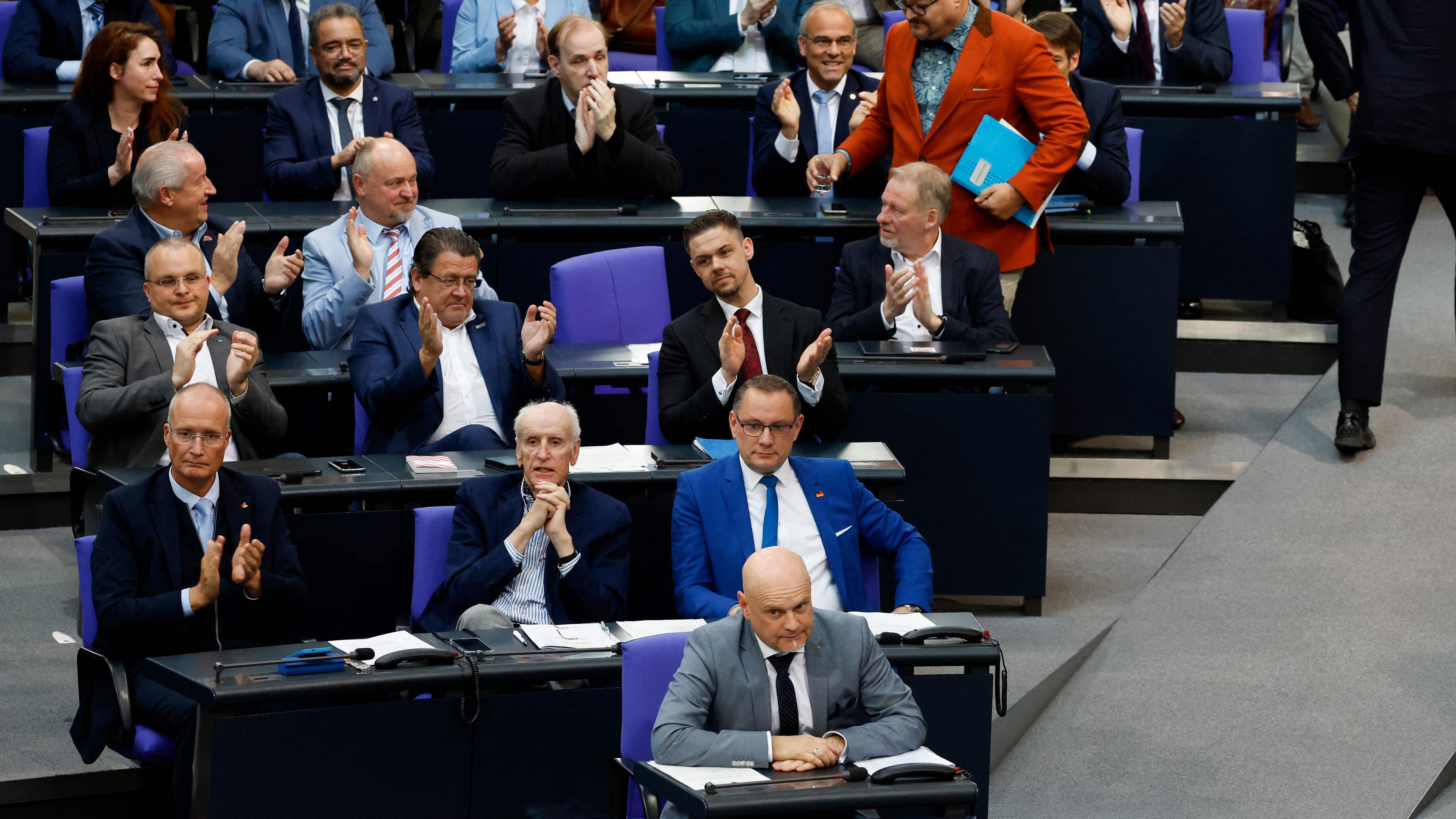 he co-leader of the far-right Alternative for Germany (AfD) party Tino Chrupalla (2nd row, R), fellow party member Albrecht Glaser (C) and AfD MP Enrico Komning (front) react as Stefan Keuter, Deputy leader of the AfD parliamentary group in the Bundestag, returns to his seat after delivering a speech during a debate at the Bundestag on the topic "Threat to our democracy - Russia, China and the role of the AfD"