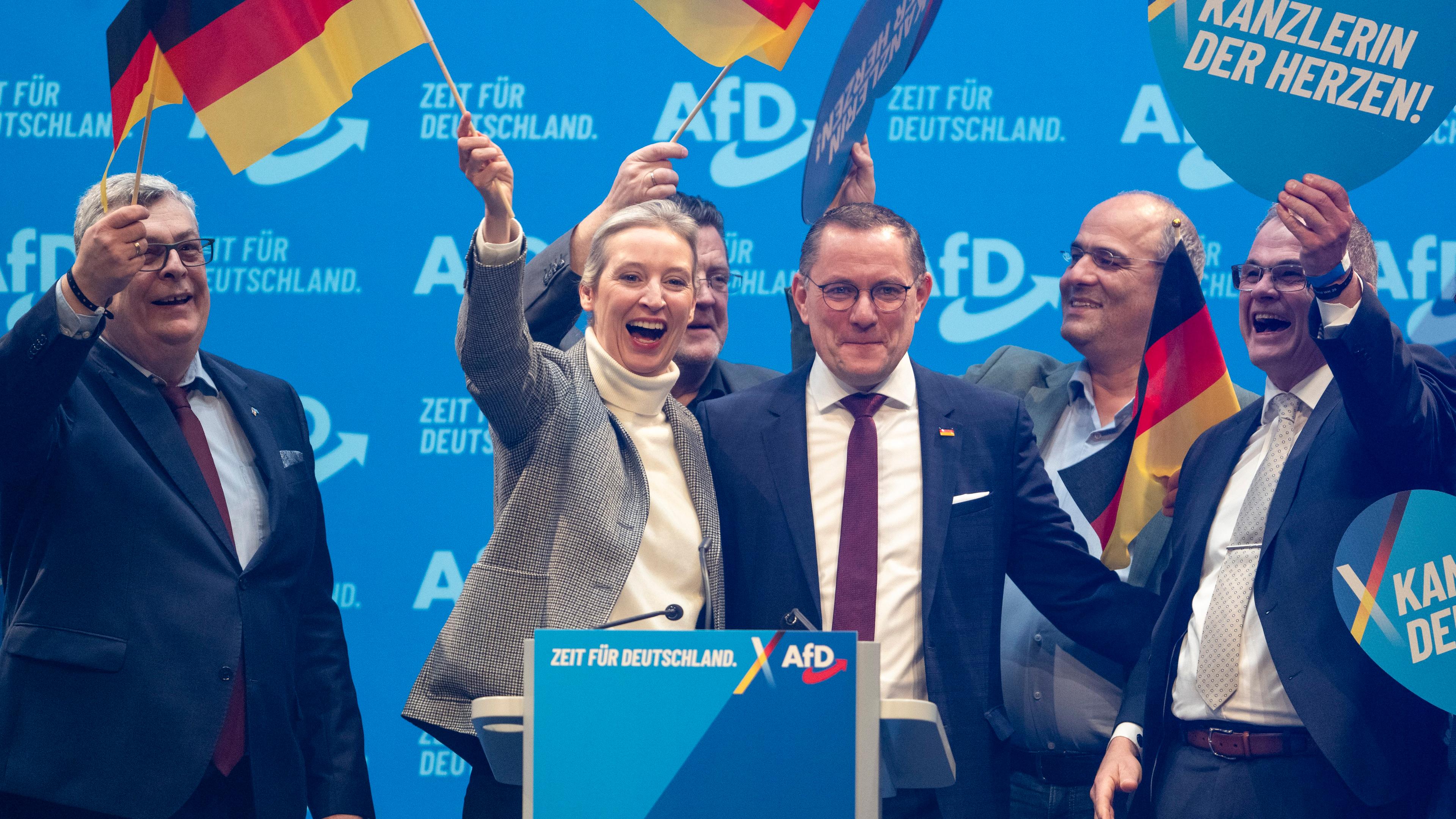 AfD Parteitmitglieder auf der Bühne, schwingen Deutschland Fahnen