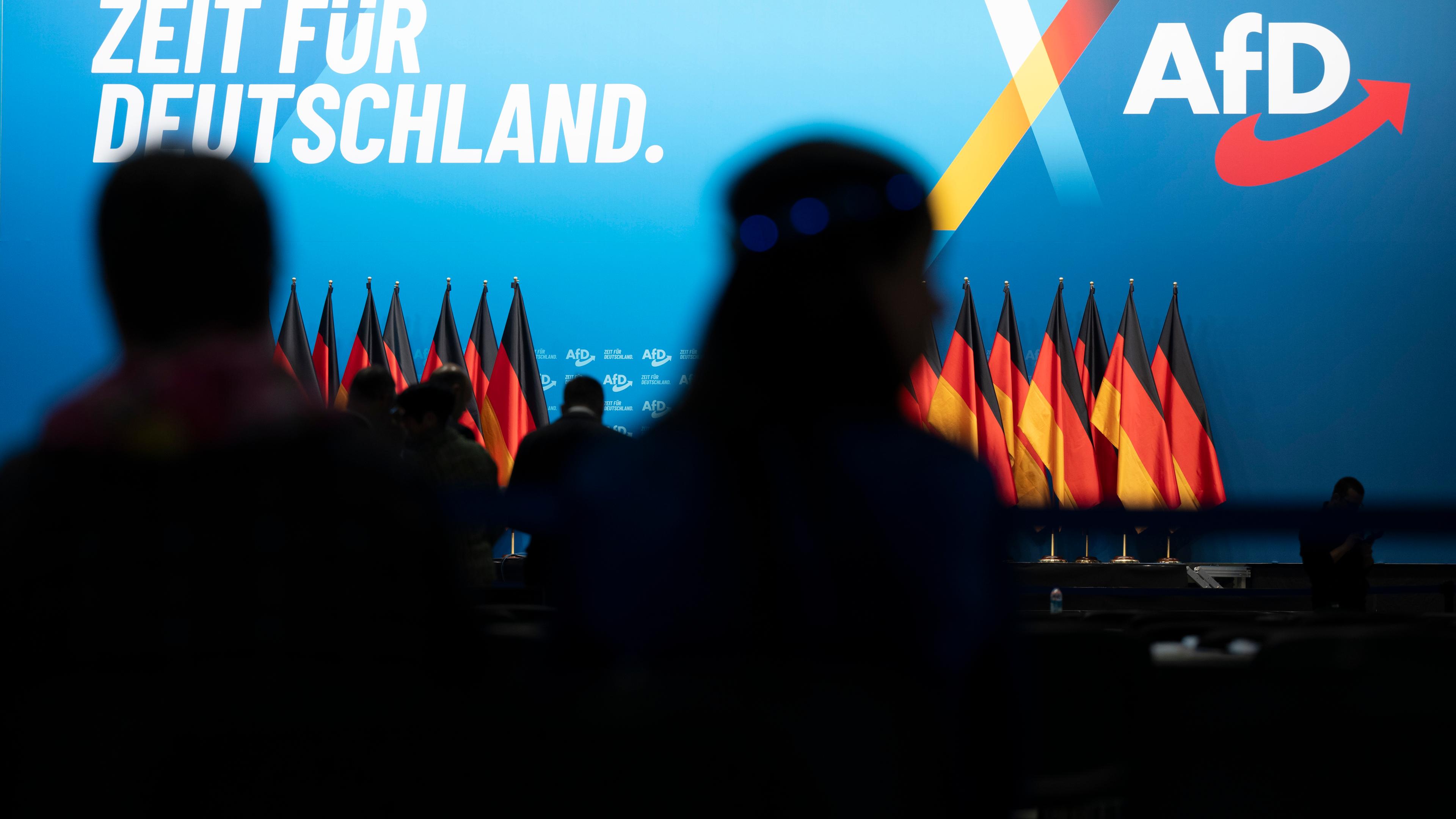 Eine Bühne mit Deutschland-Flaggen, AfD-Werbung im Hintergrund.