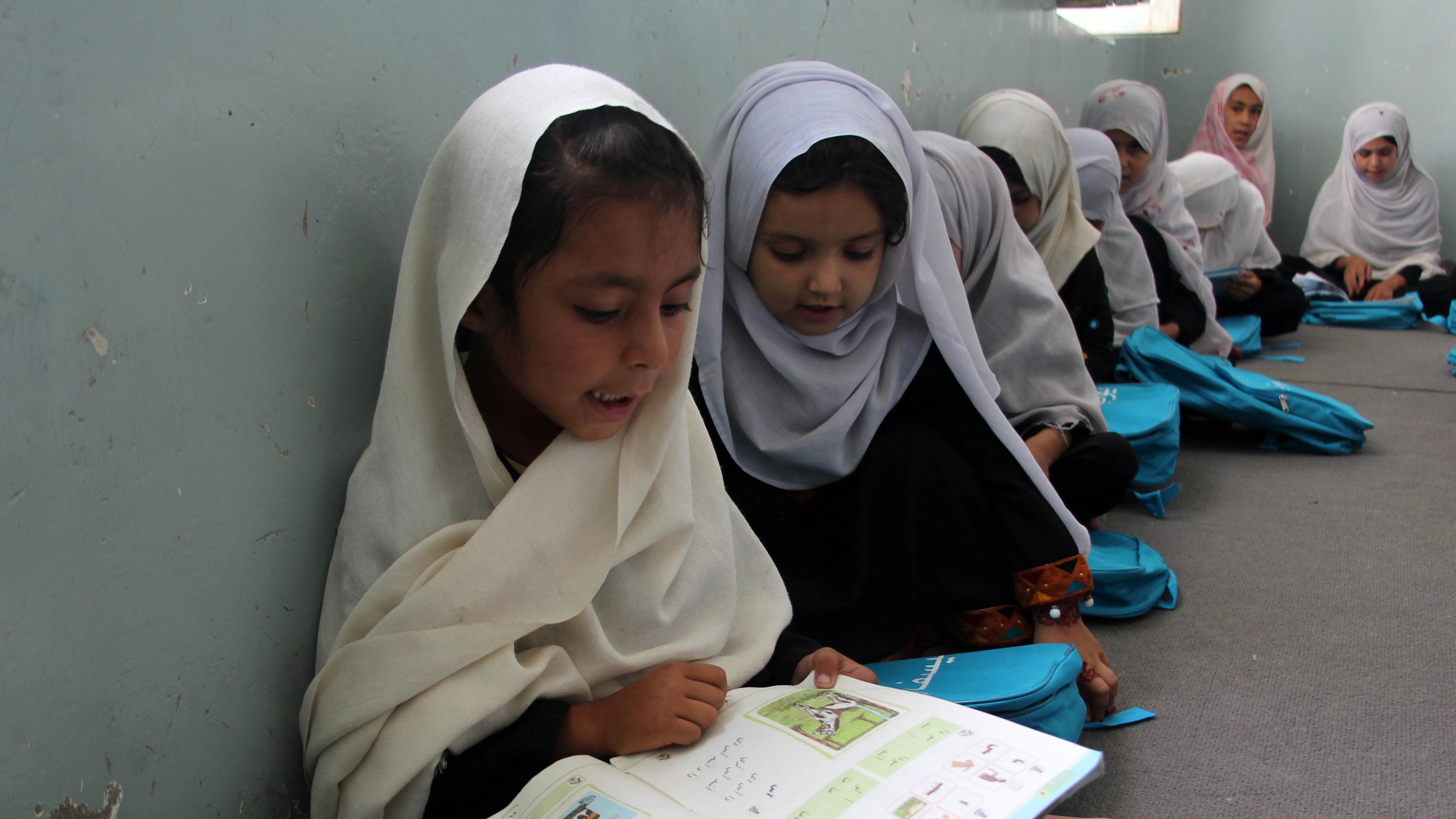 Afghanische Mädchen sitzen in einer Grundschule in Kandahar auf dem Boden.