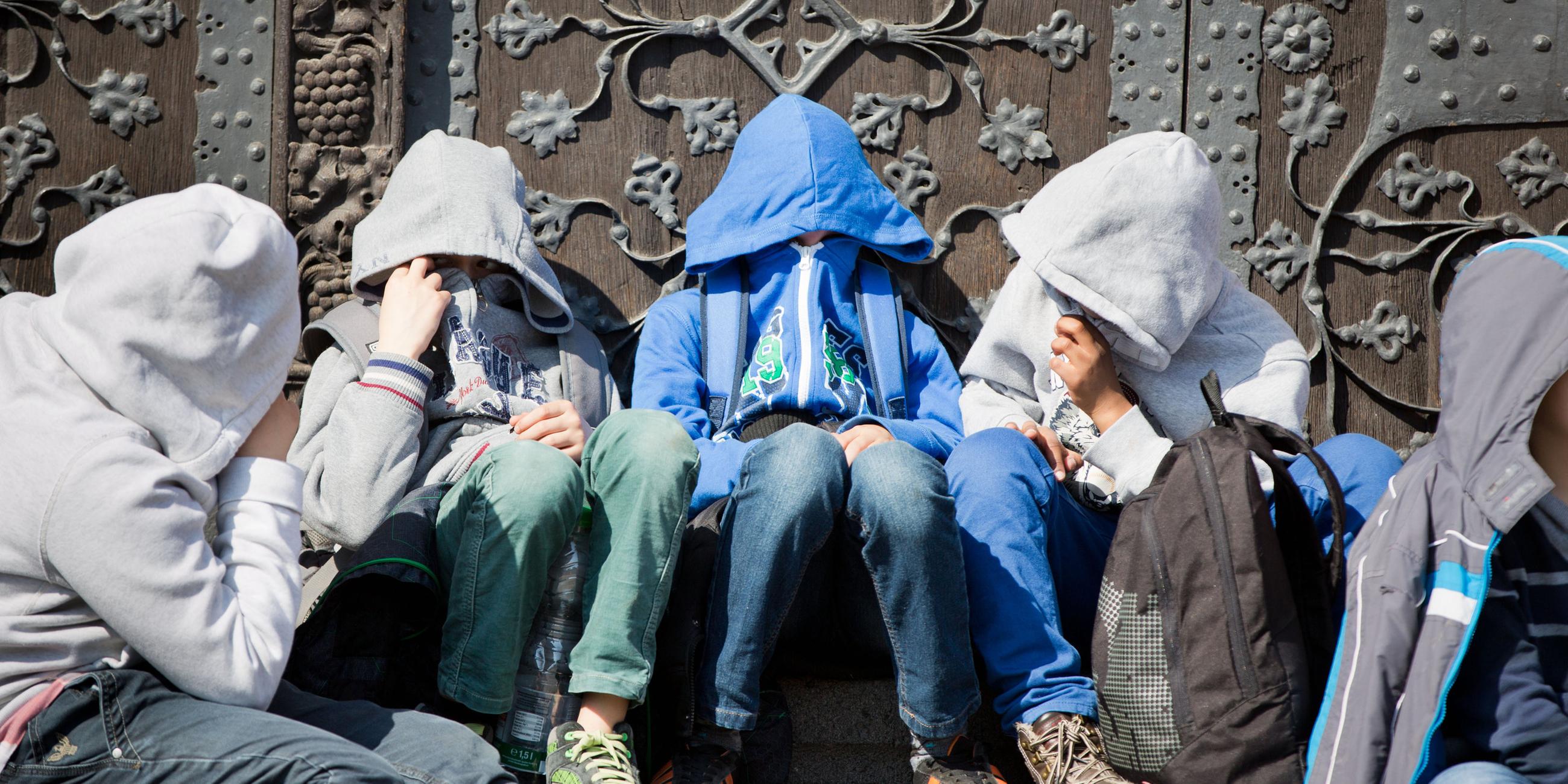 Eine Gruppe von Schülern bei einer Pause. Sie tragen Kapuzenpullover.