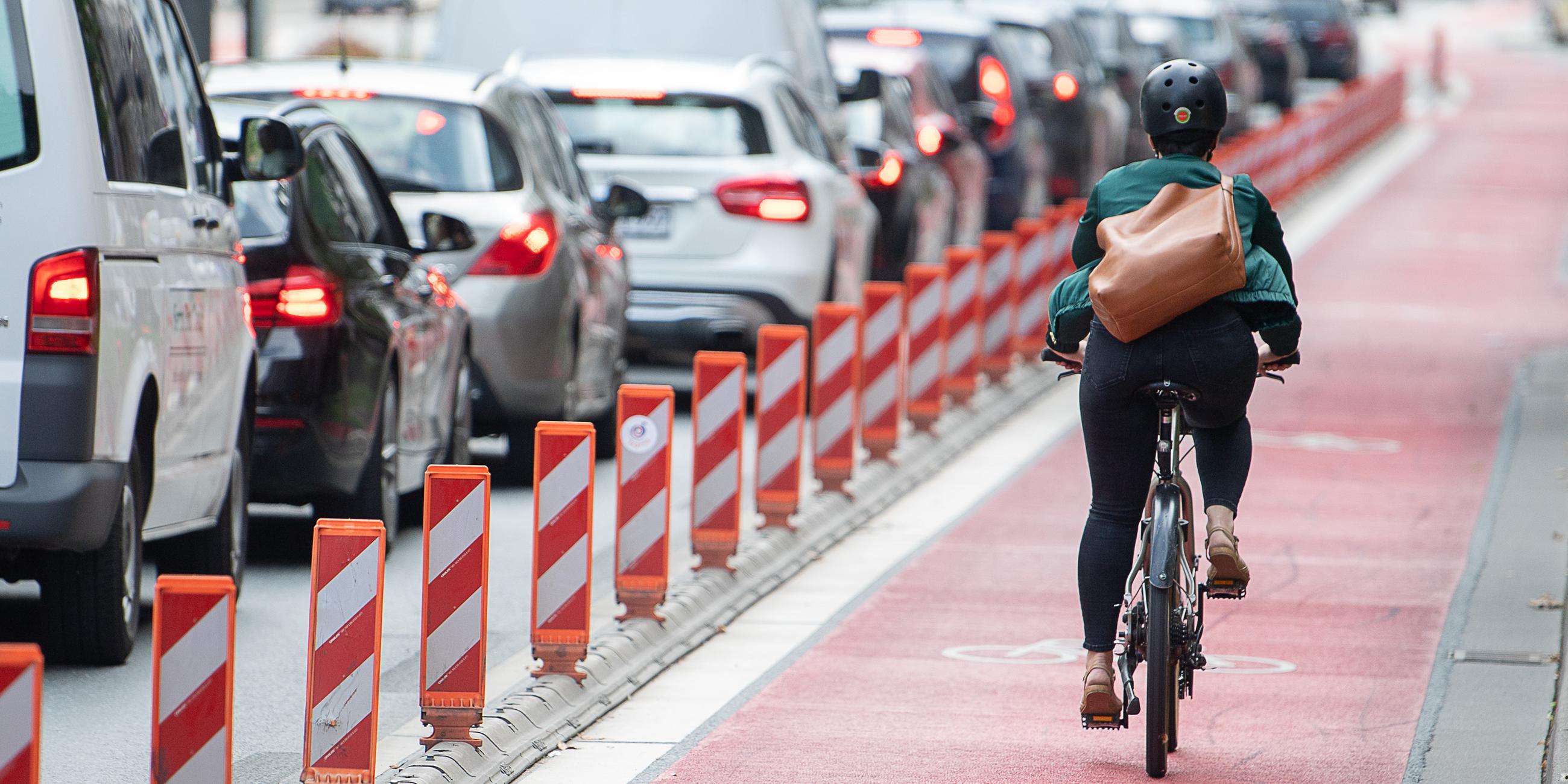 Eine Radfahrerin fährt auf einem Fahrradweg, der parallel zu einer Straße verläuft