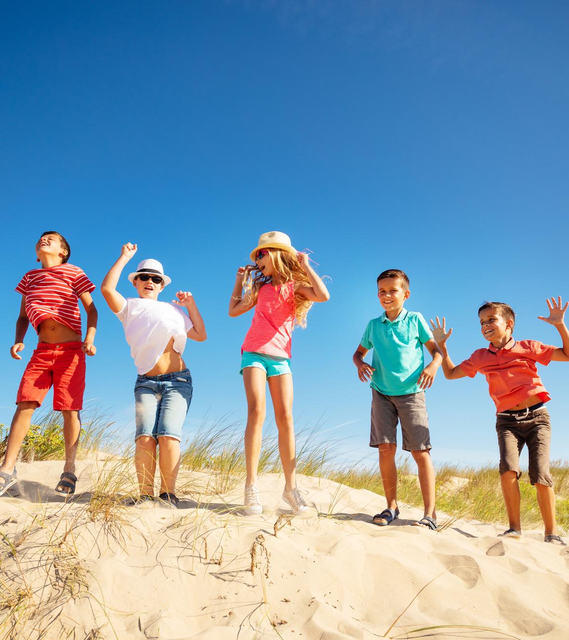 Kinder tanzen auf einer Sanddüne