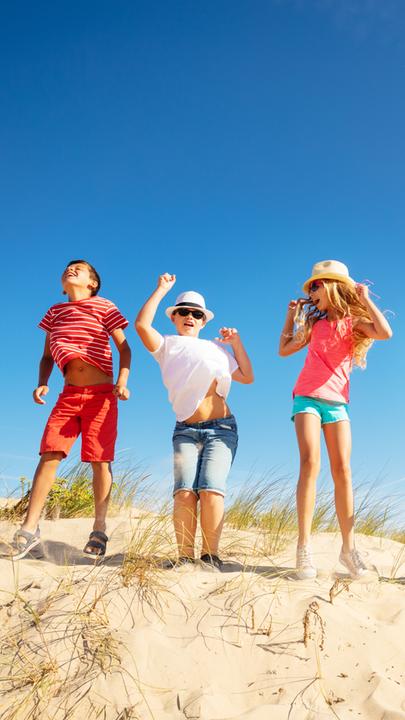 Kinder tanzen auf einer Sanddüne