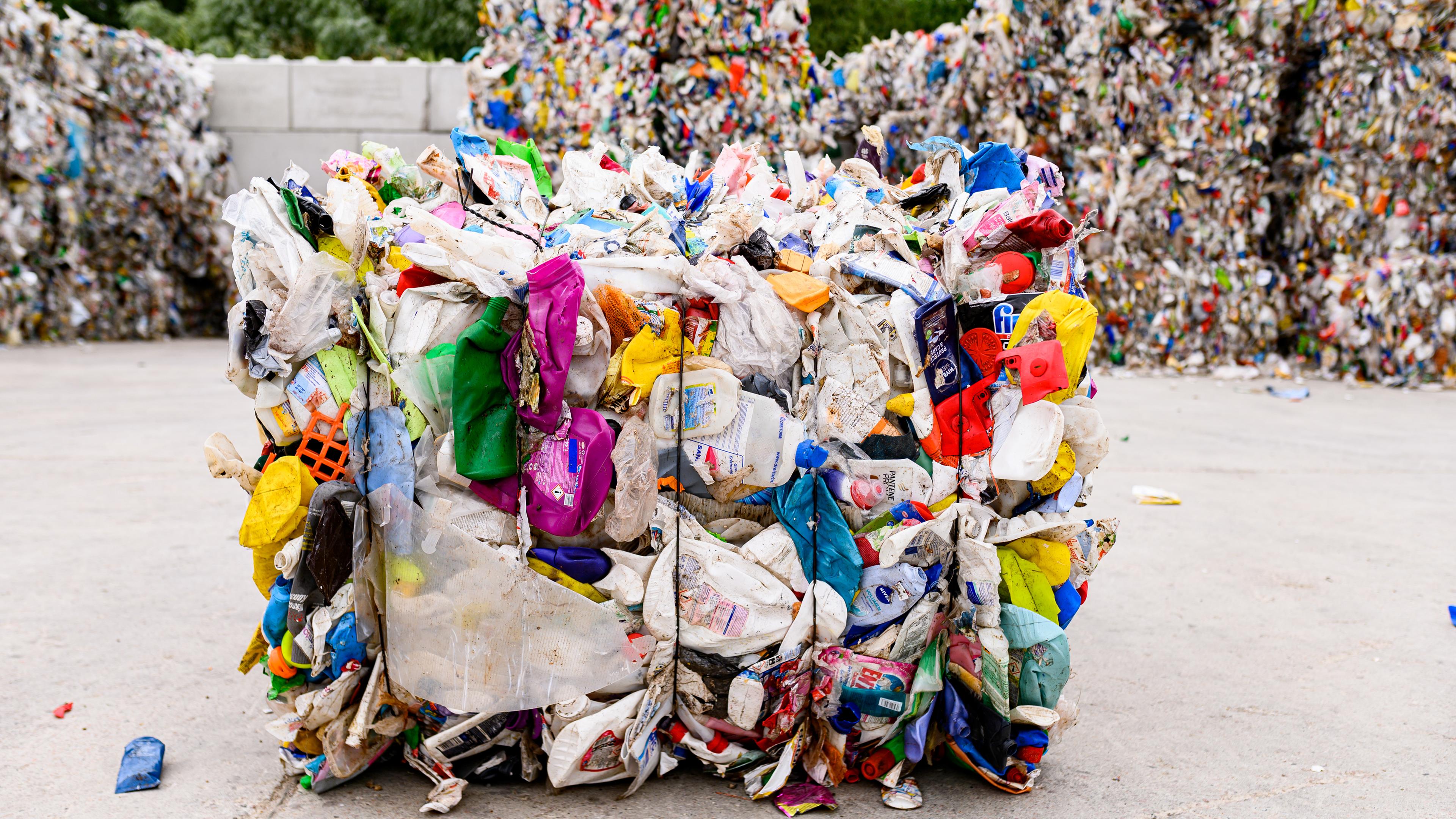 Man sieht auf dem Bild Plastikmüll zusammengepresst zu großen Würfeln in einer Mülldeponie. 