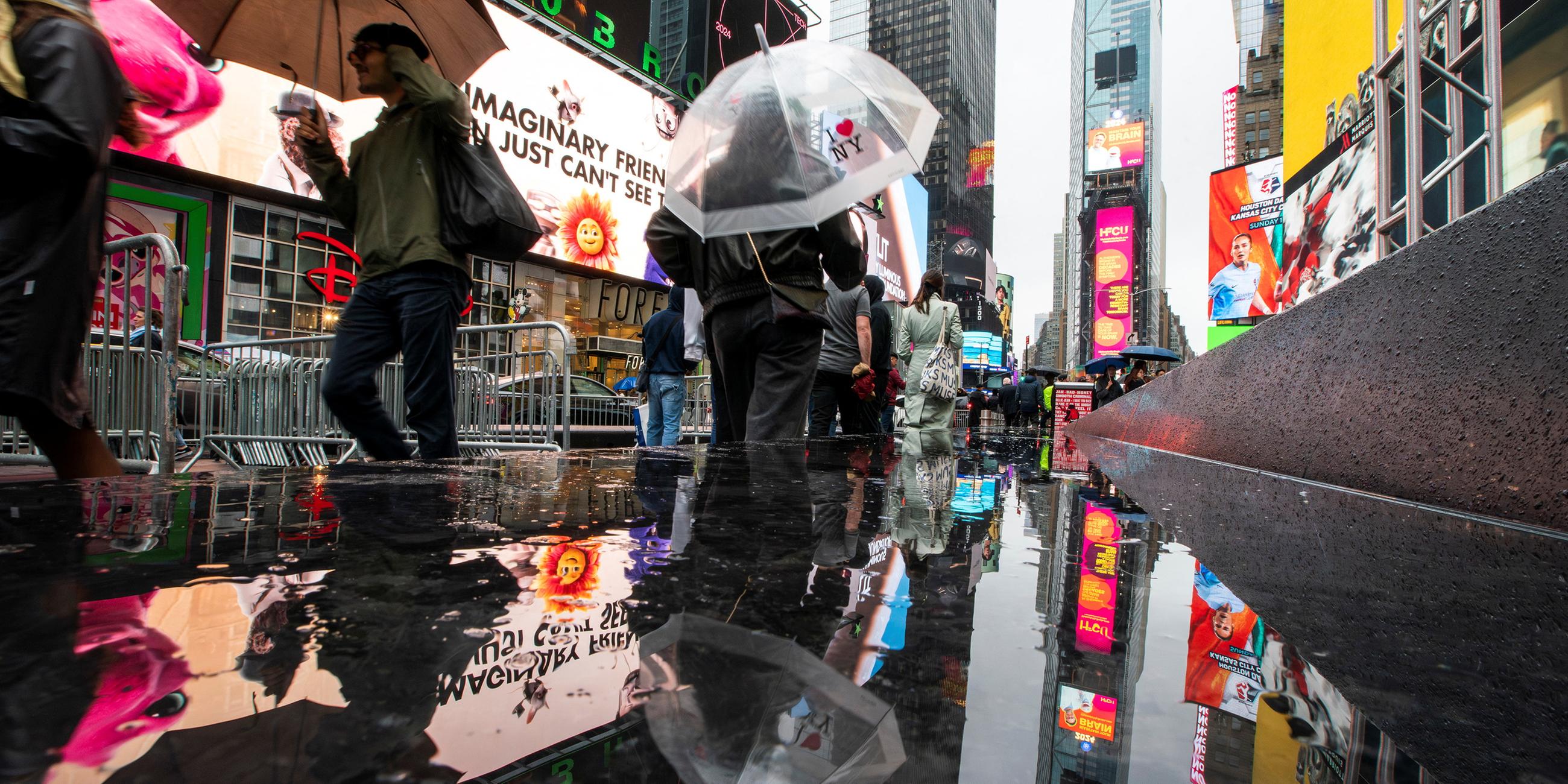 People make their way around Times Square during a rainy day in New York
