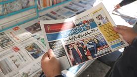 An Iranian man looks at a newspaper with a photo of Trump and Harris, in Tehran