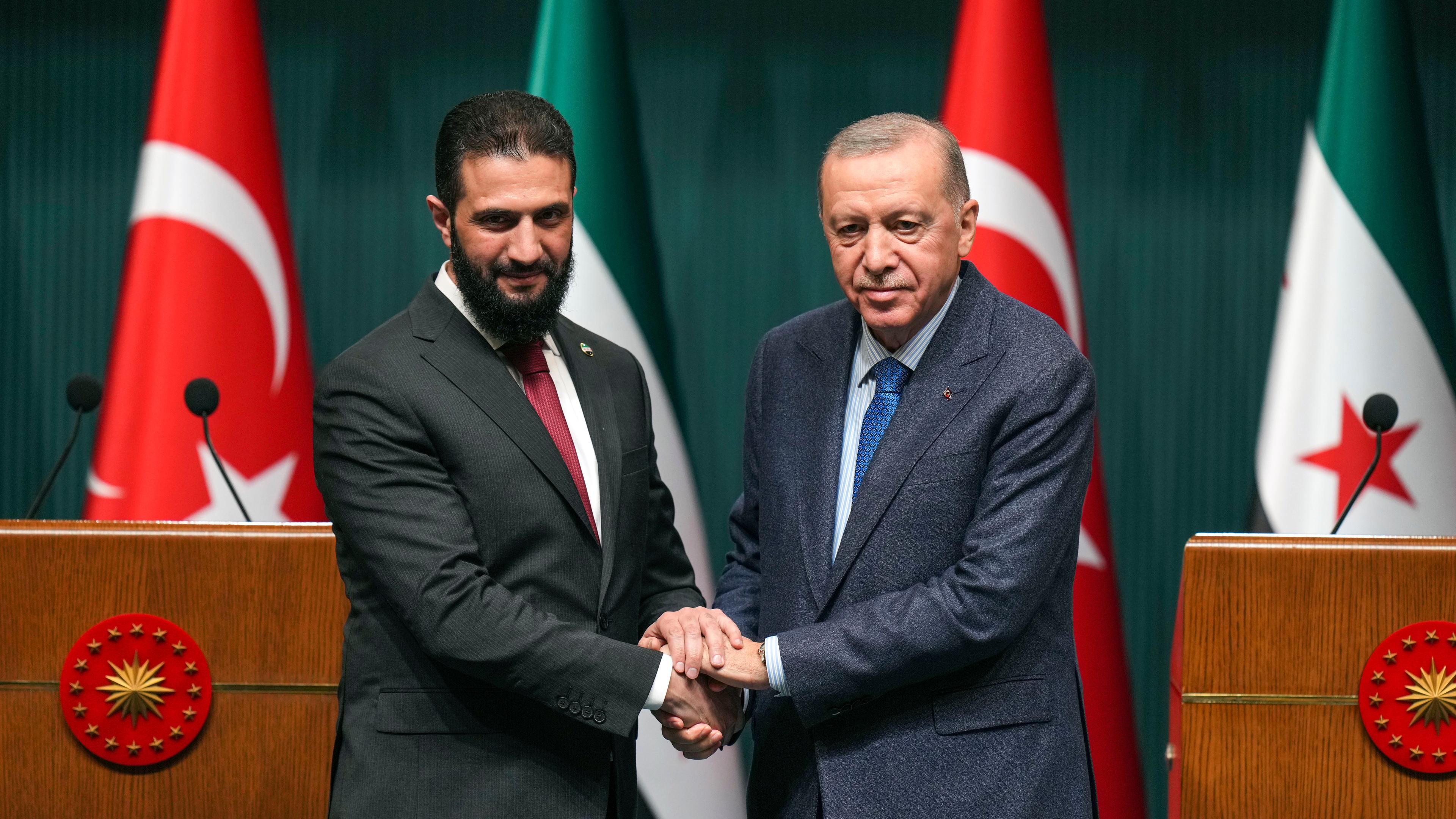 Der türkische Präsident Recep Tayyip Erdogan (r) und Syriens Übergangspräsident Ahmed al-Scharaa geben sich nach ihrem Treffen auf einer gemeinsamen Pressekonferenz im Präsidentenpalast in Ankara die Hand.