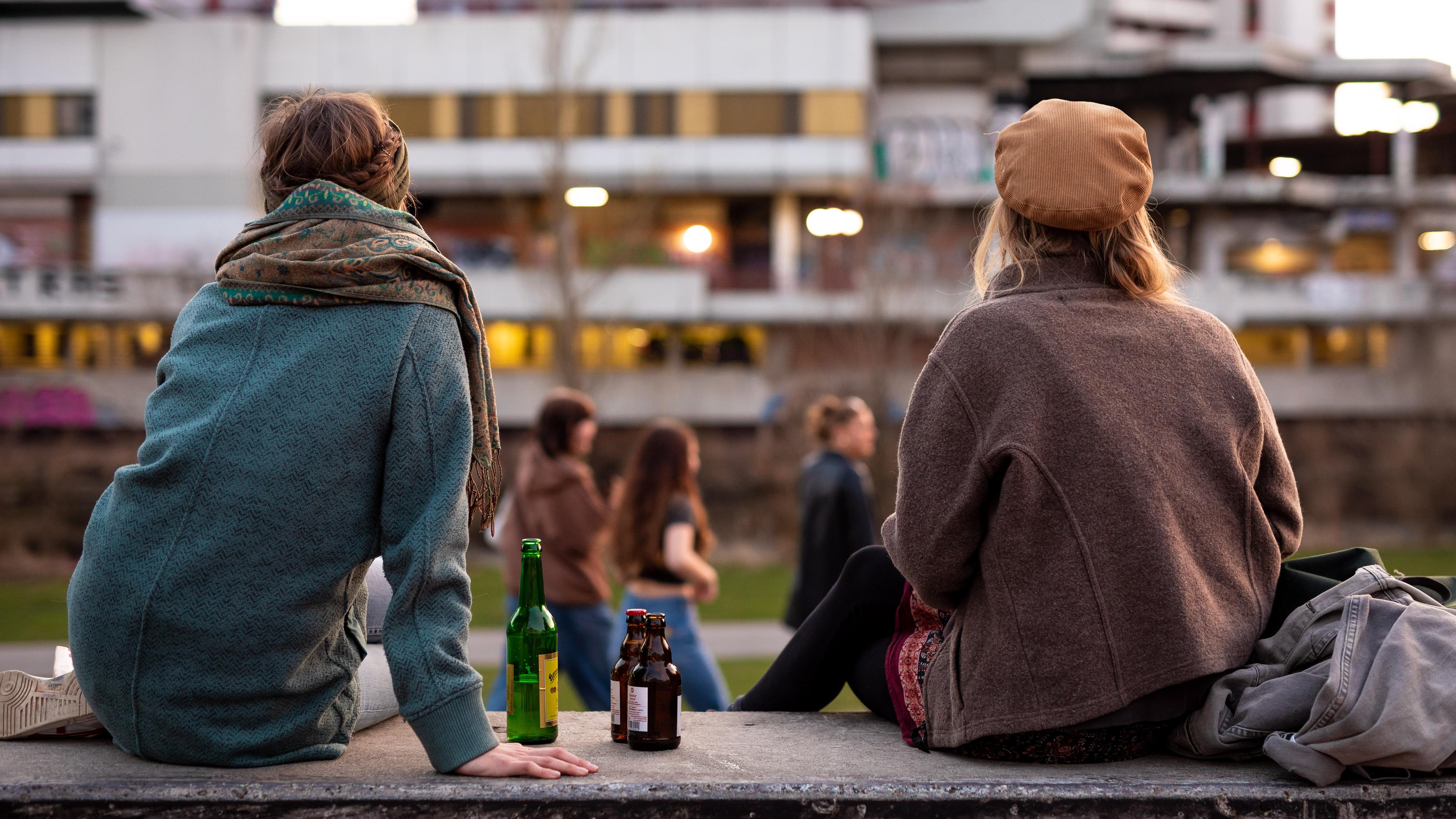 Junge Leute sitzen auf der Mauer, daneben leere Alkoholflaschen.