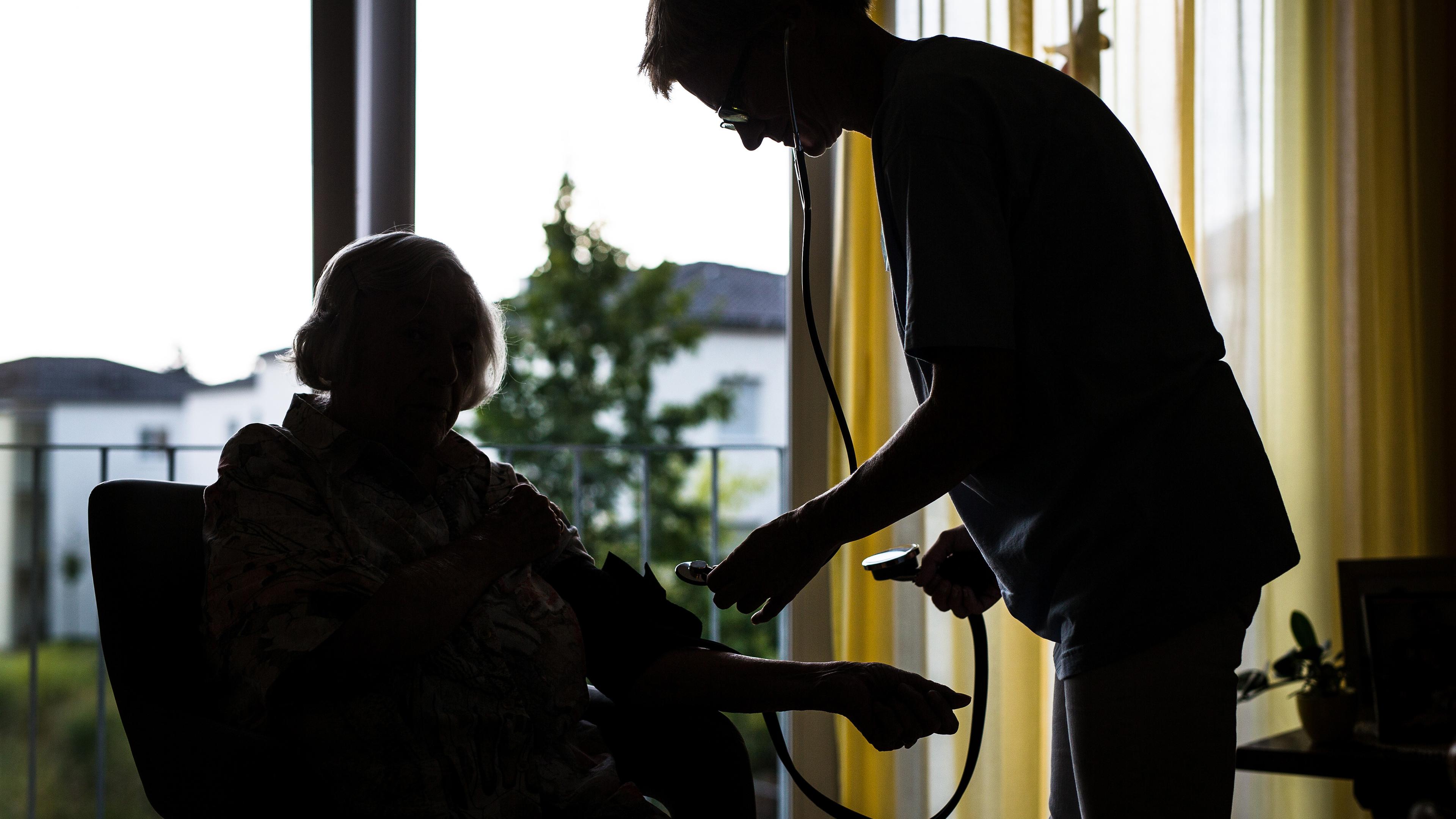 Eine Pflegekraft kümmert sich in einem Pflegeheim um eine ältere Dame und kontrolliert den Blutdruck, aufgenommen am 23.08.2018